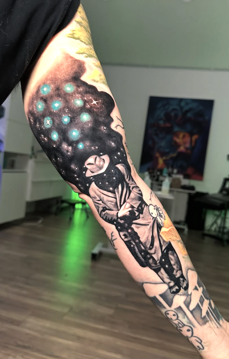 Tattoo of a person riding a bicycle with a galaxy and stars in the background.