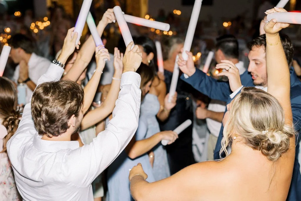People in formal attire celebrating at a wedding reception with glow sticks