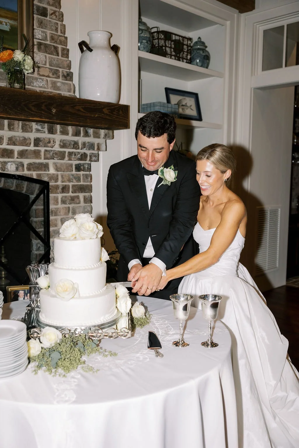 Bride and groom cutting a wedding cake decorated with white flowers at a wedding reception.
