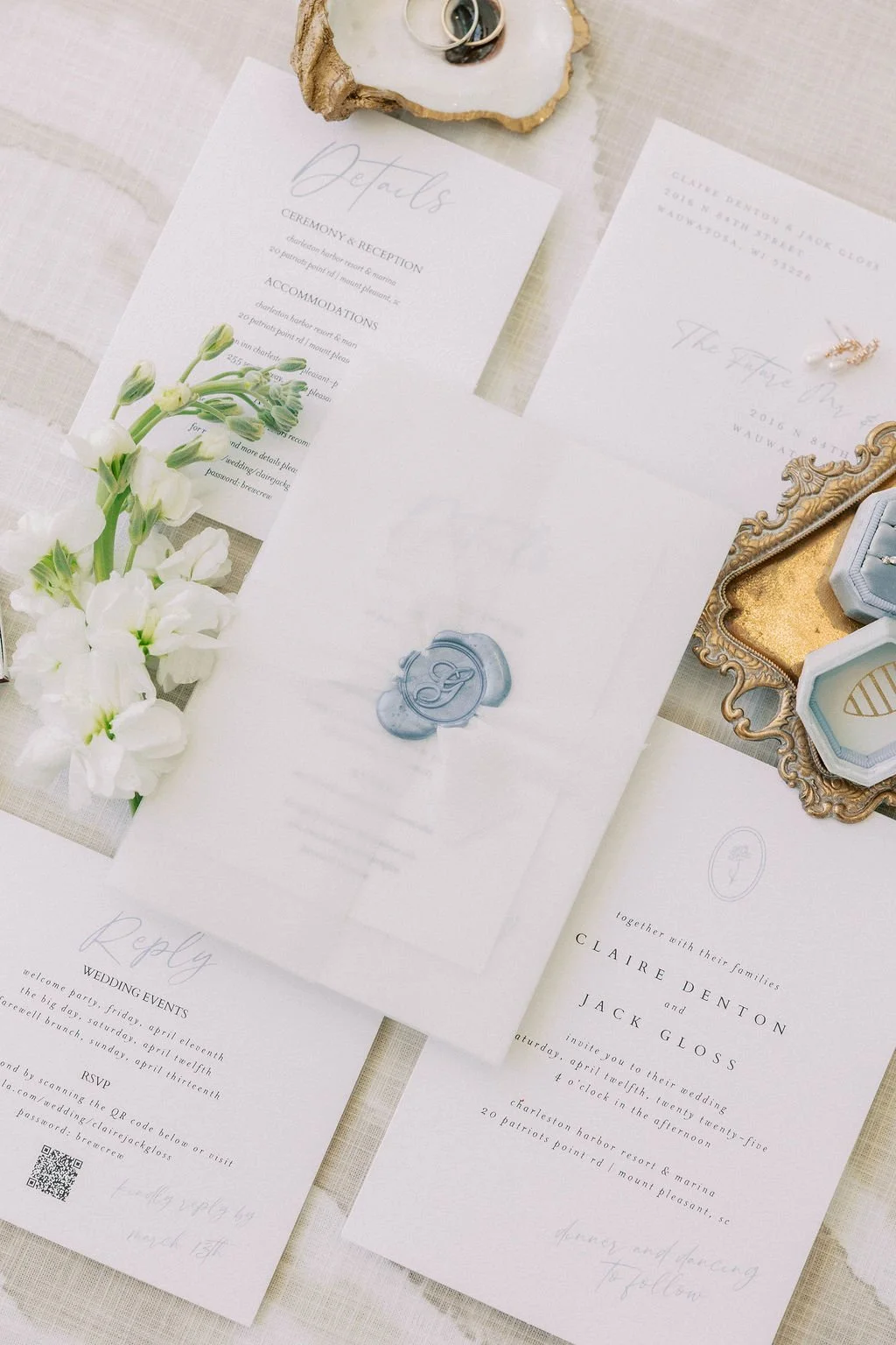 Wedding invitation suite with floral accents, wax seal, pearl jewelry, and decorative tray.