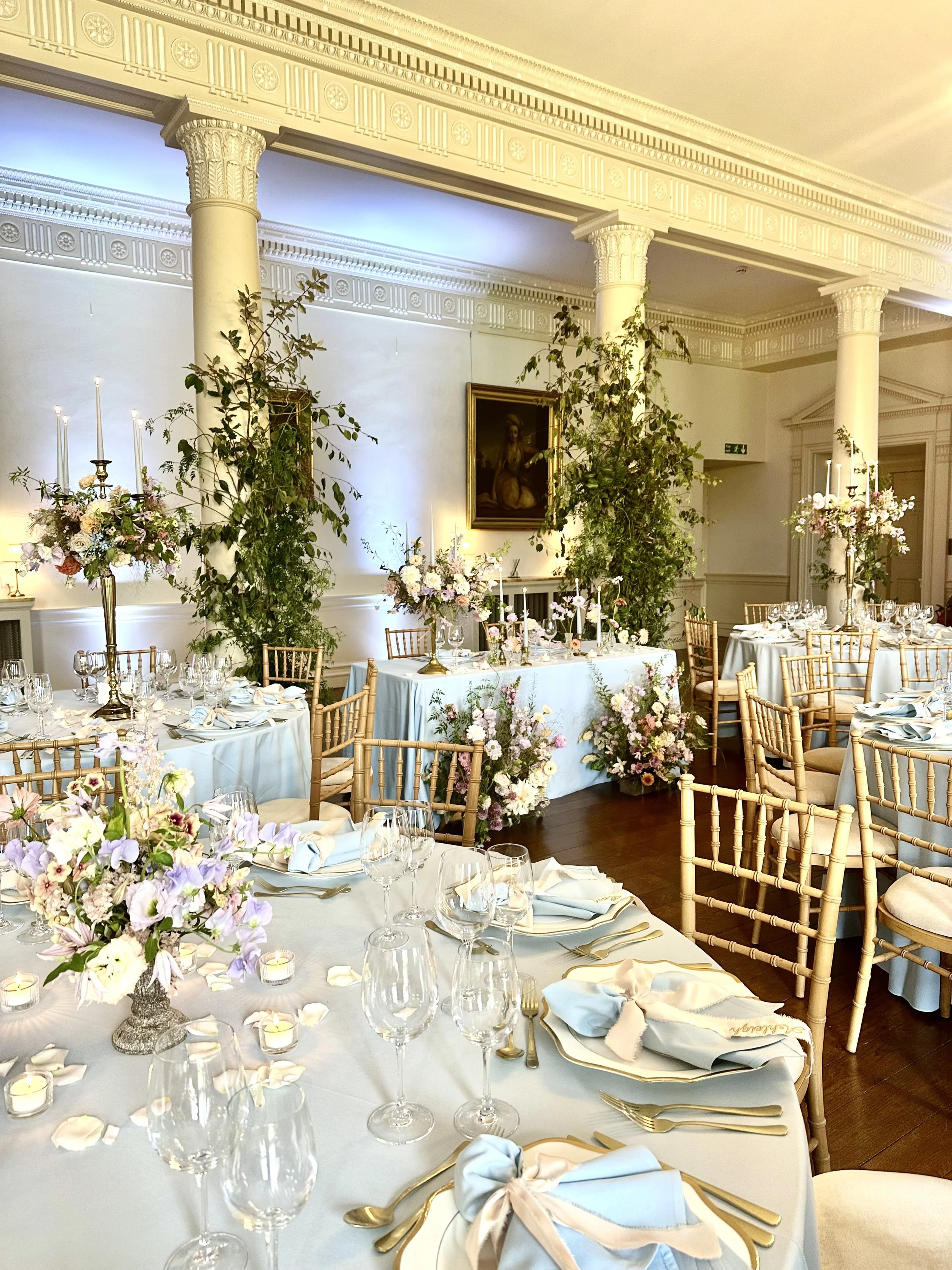 Elegant dining room at North Cadbury Court in Somerset, decorated for a wedding reception with floral centerpieces, candles, and gold accents.