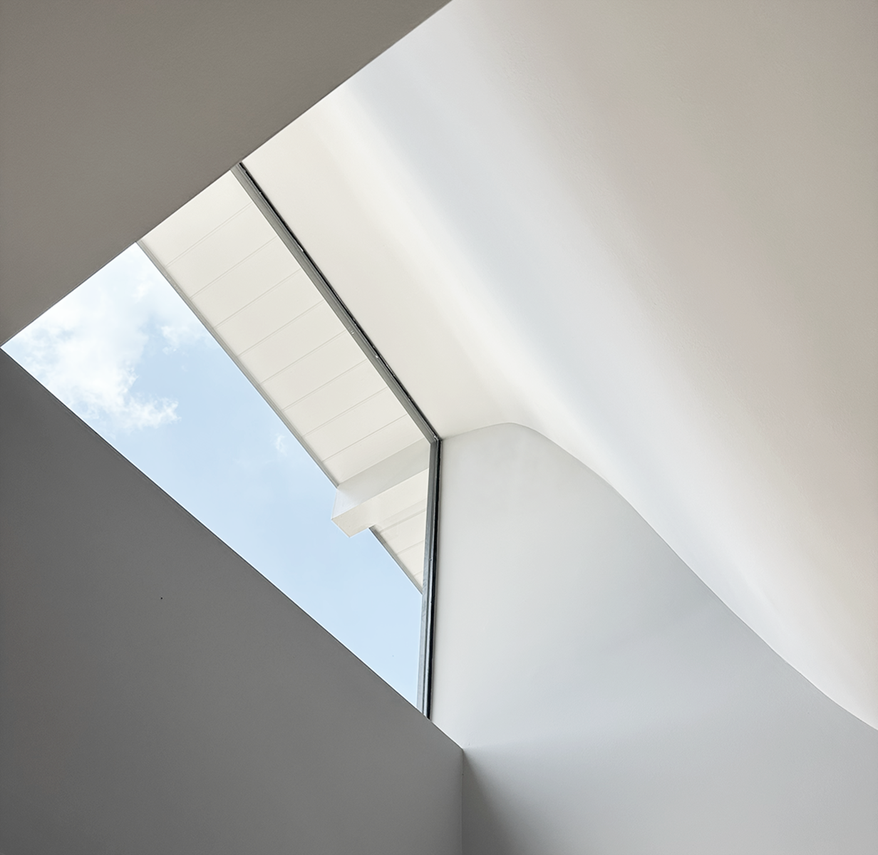 Interior view of a modern ceiling with a skylight showing a blue sky with some clouds in houston.