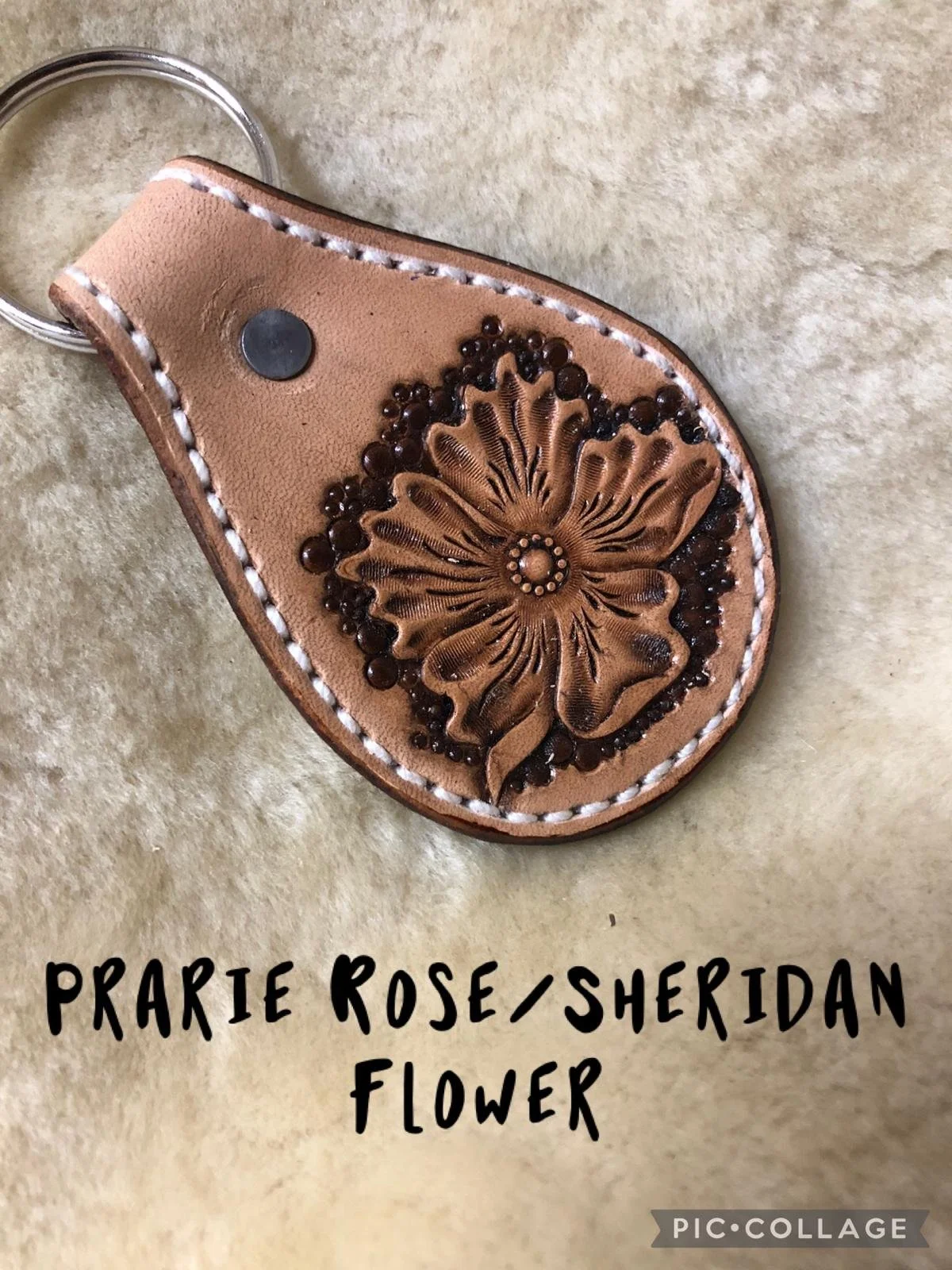 Leather keychain with an embossed prairie rose or sheridan flower design on a soft beige background.