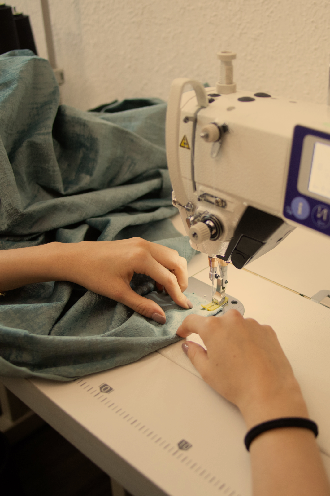 Hands working with an industrial sewing machine, sewing.