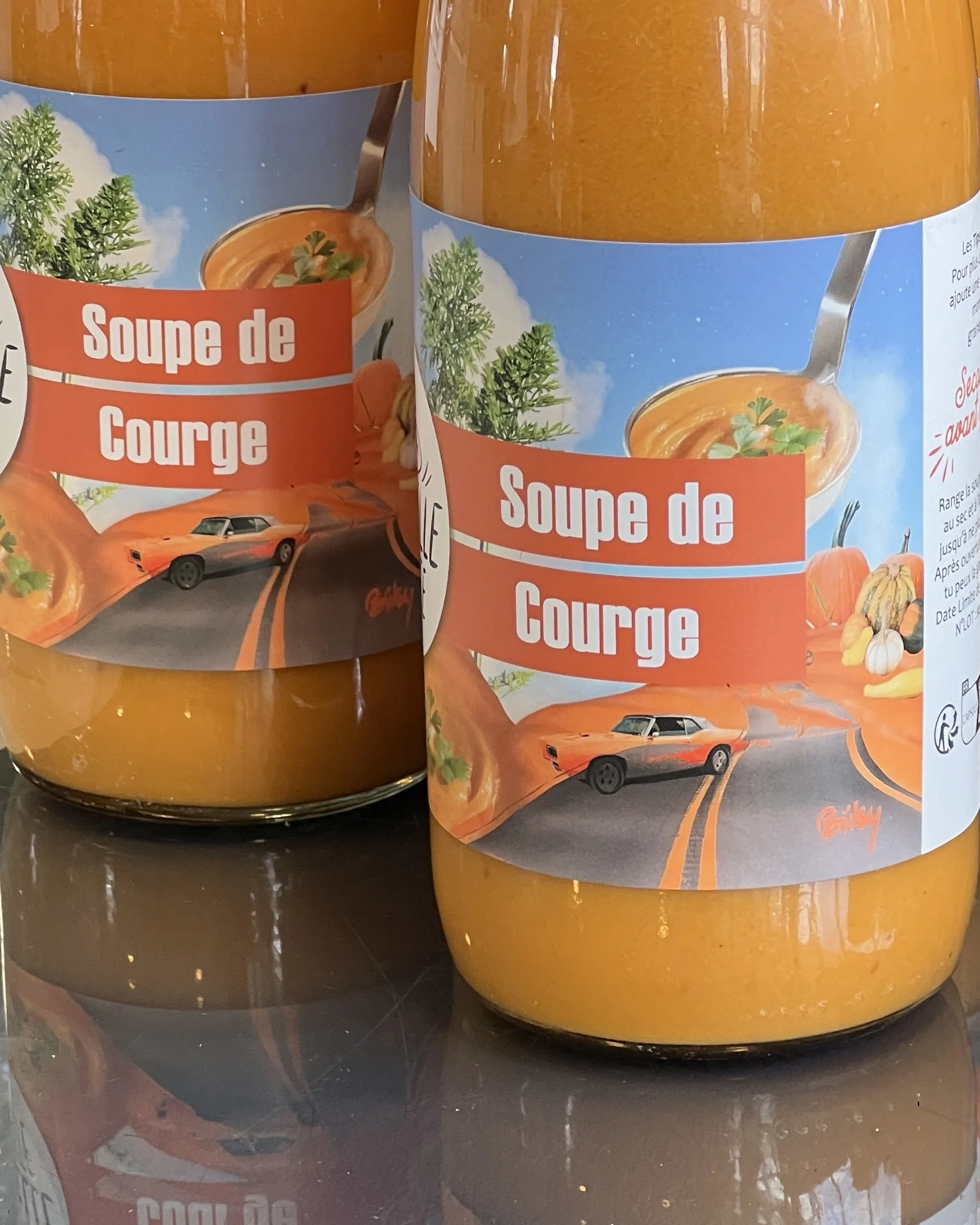Bocal de soupe de courge avec un label illustrant une voiture de sport orange, une courge, et un bol de soupe à la citrouille, le tout sur un fond bleu avec des dessins de légumes.