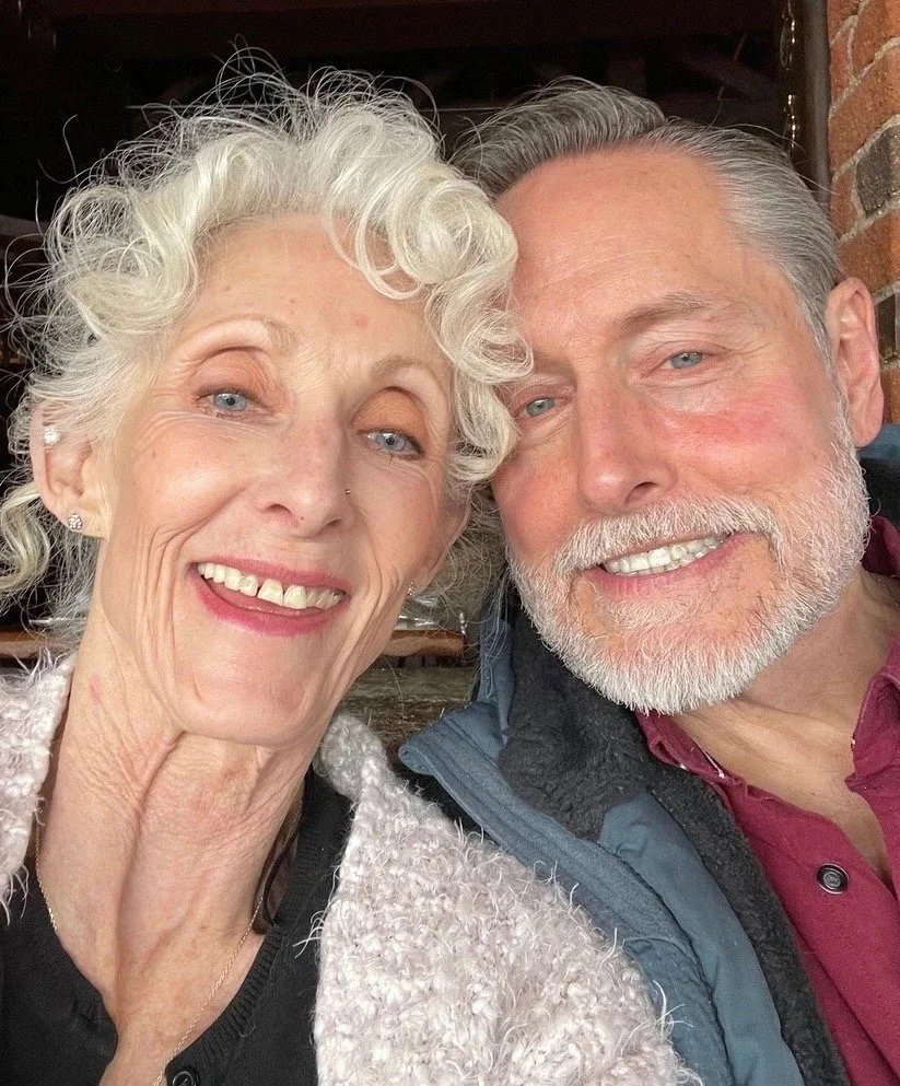 A river inwith mist rising above the water, surrounded by a forest of pine trees, with the sun setting or rising in the sky.