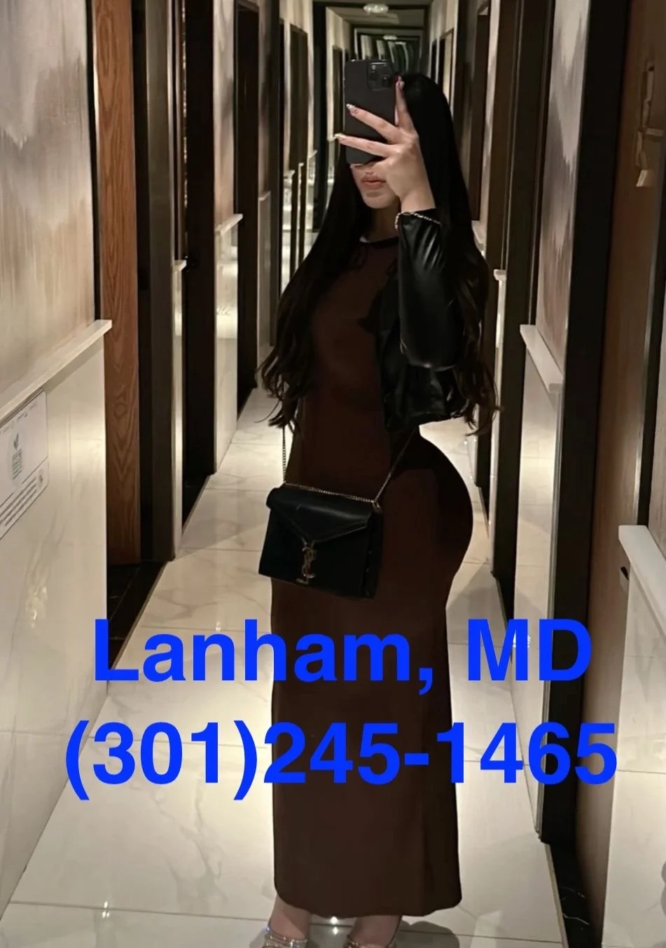 A woman taking a mirror selfie in a hallway, wearing a brown dress and black jacket, carrying a black purse, with text overlay showing contact information for Lanham, MD.