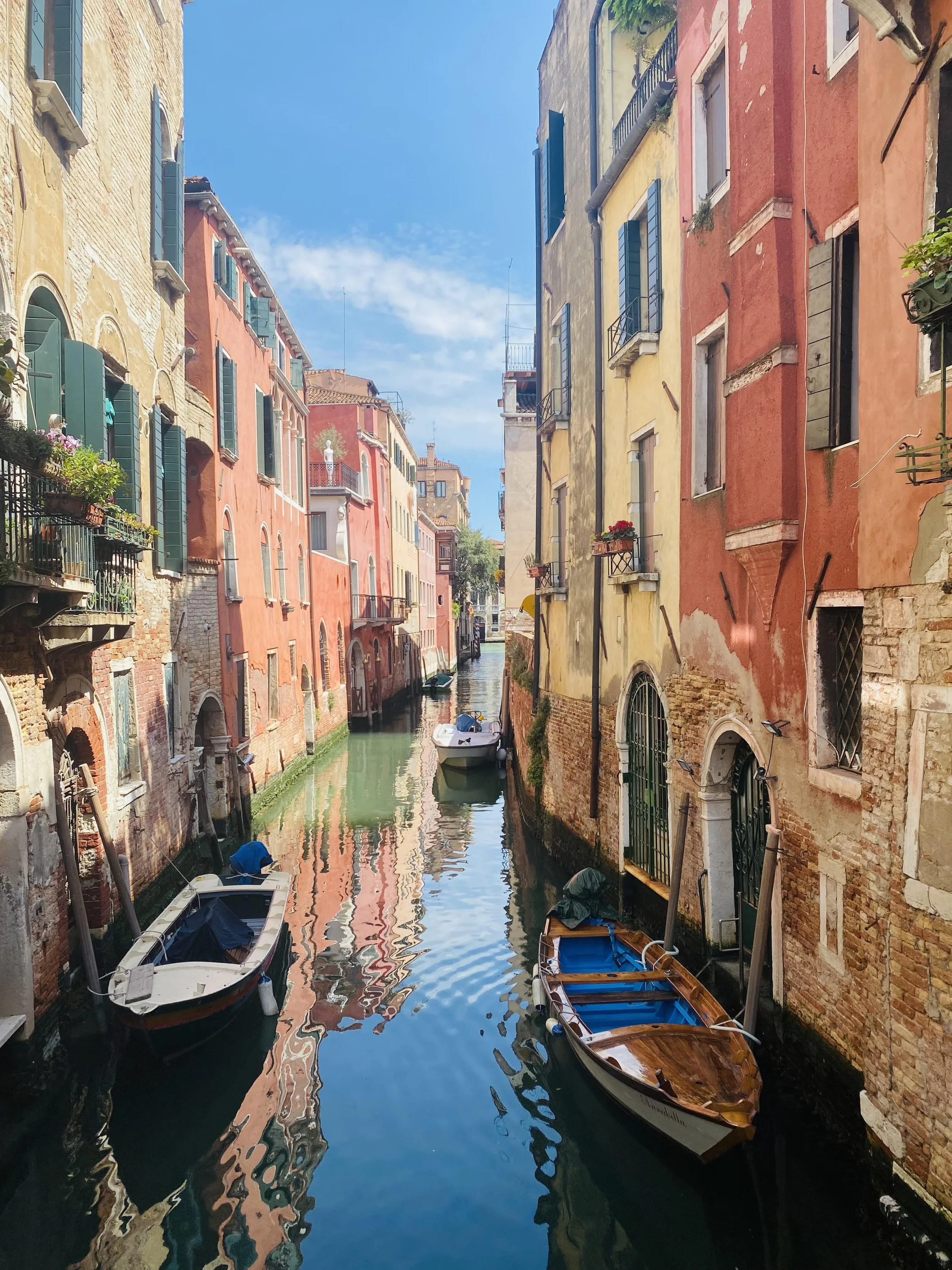 Colorful buildings along a narrow canal with boats docked on the sides, typical of Venice, Italy.