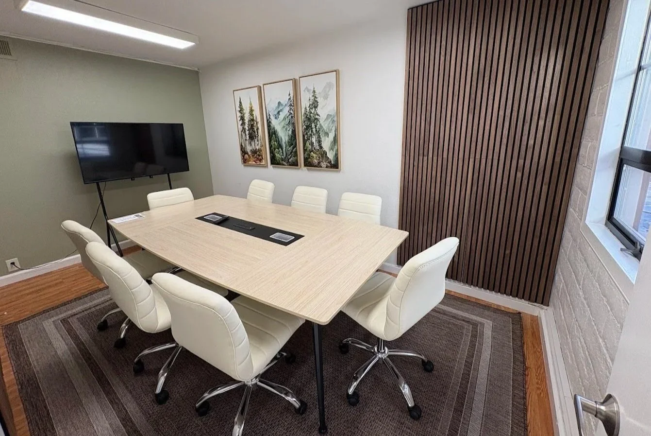 Professional meeting room in Benicia with 8 chairs, a table, a presentation screen, acoustic panels, and a white board.