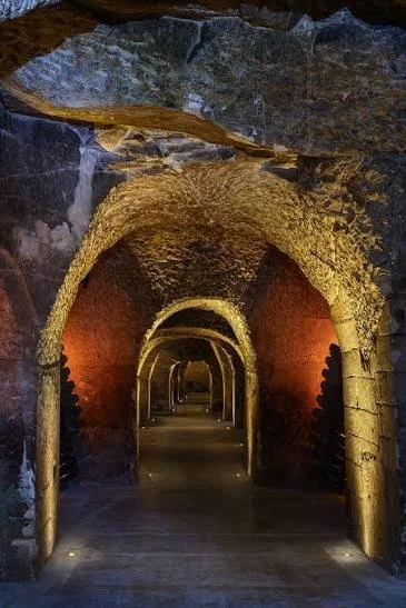 Lit stone wine cellar tunnels with vaulted arches