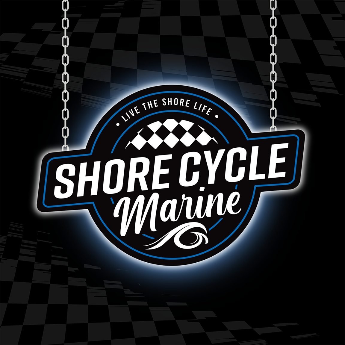 A neon-style sign with the text 'Shore Cycle Marine' and the slogan 'Live the Shore Life,' featuring checkered pattern and a wave graphic, hanging with chains against a dark background.