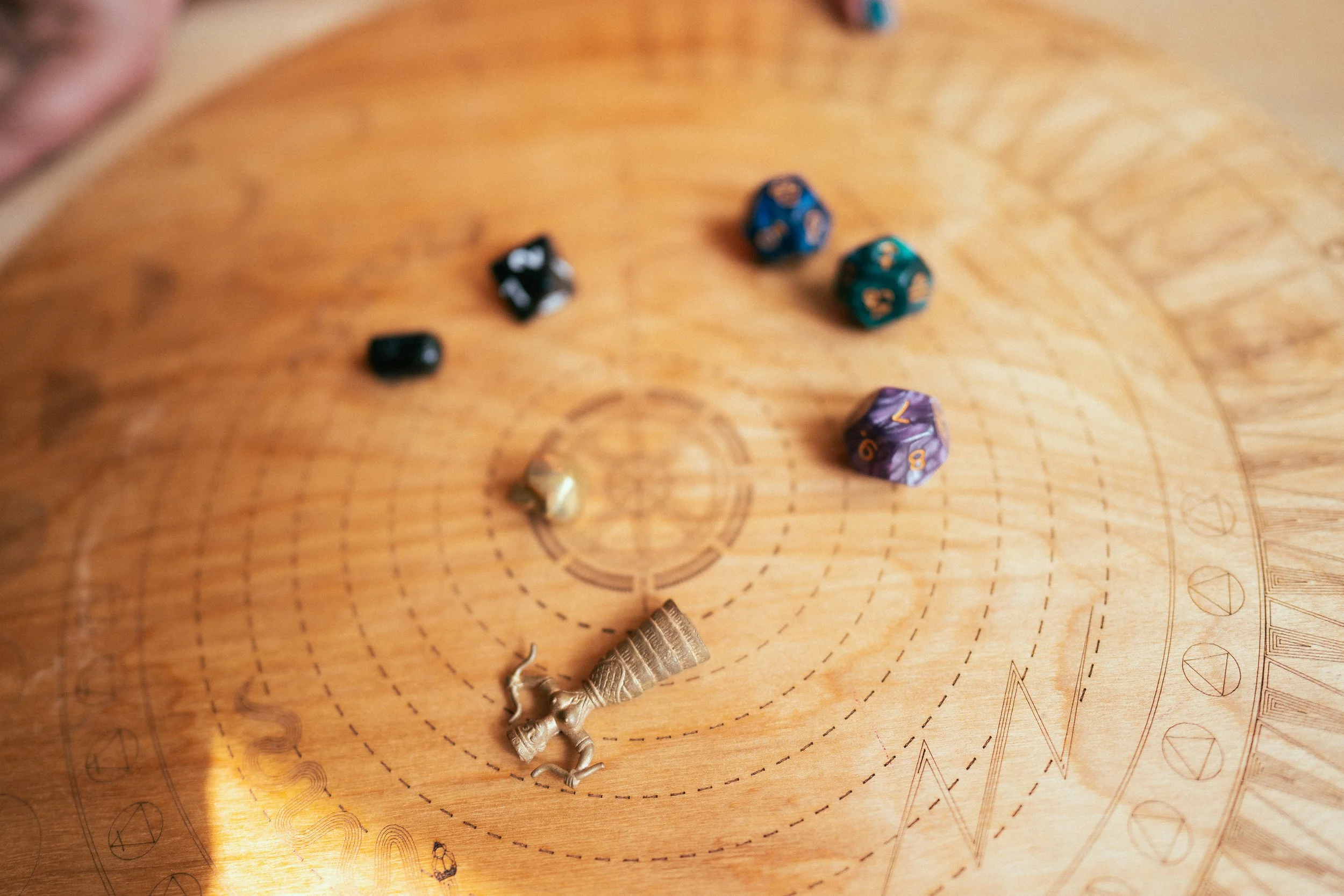 Several polyhedral dice in various colors and sizes scattered on a wooden gaming table.