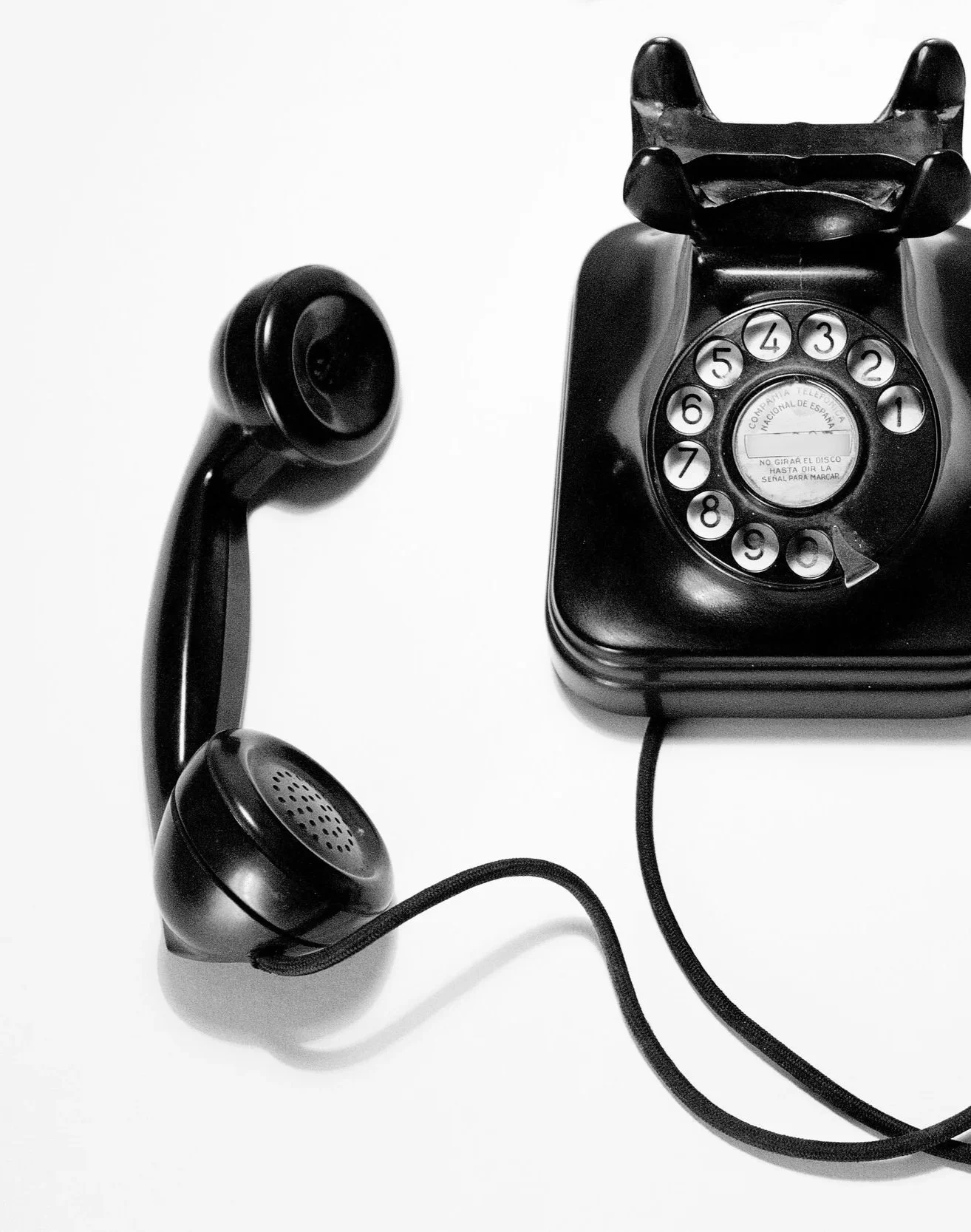 Black rotary telephone with a cord and a vintage black desk phone.