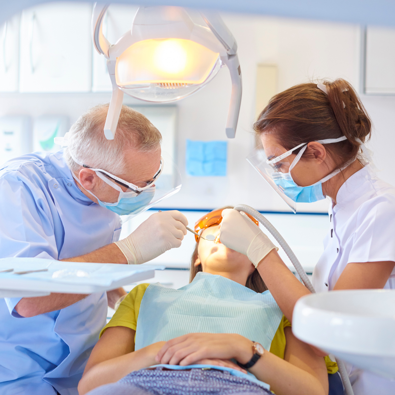 Dentists performing a dental procedure on a young patient in a dental office.