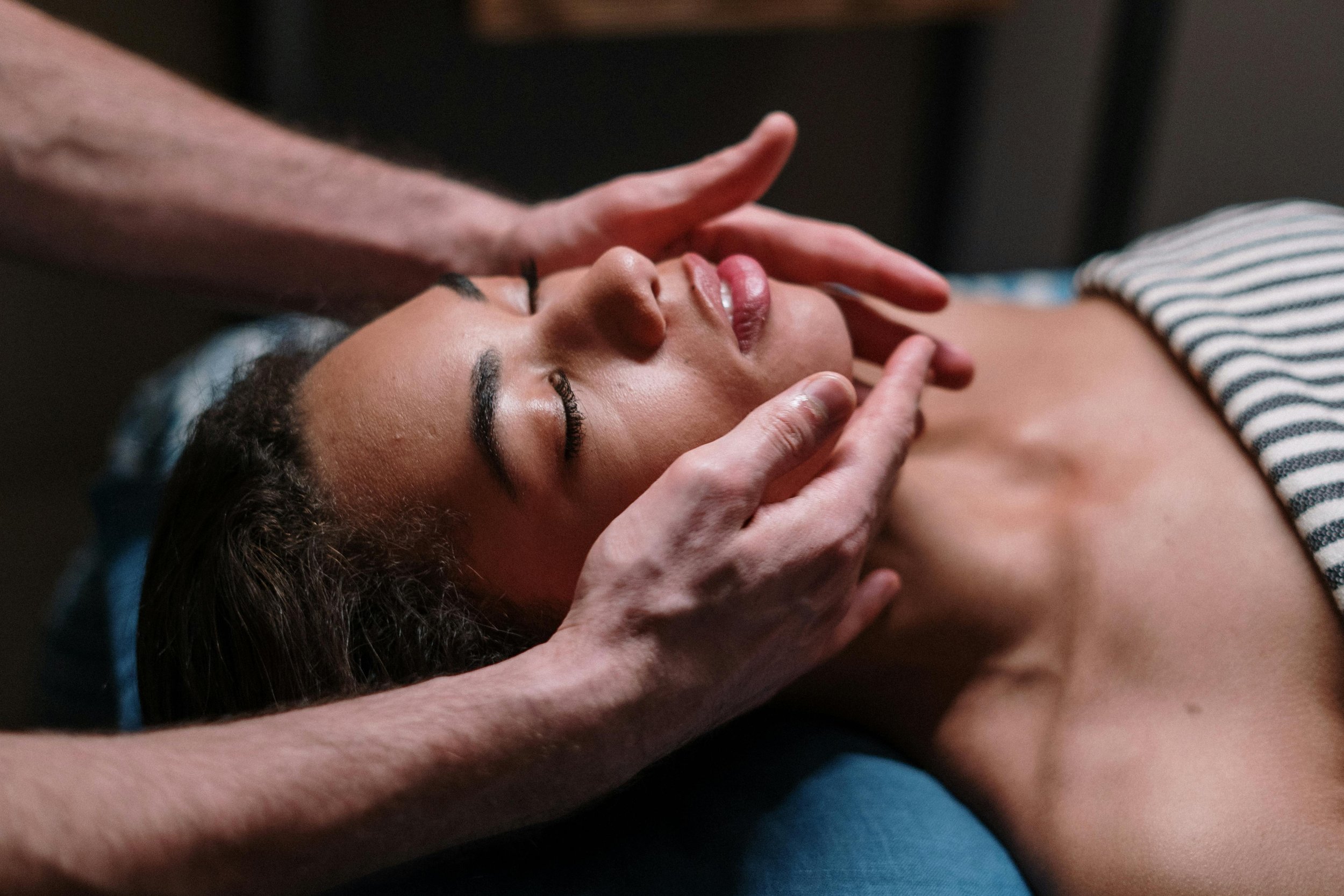 Person receiving a facial massage or therapy, with hands gently touching their face and neck