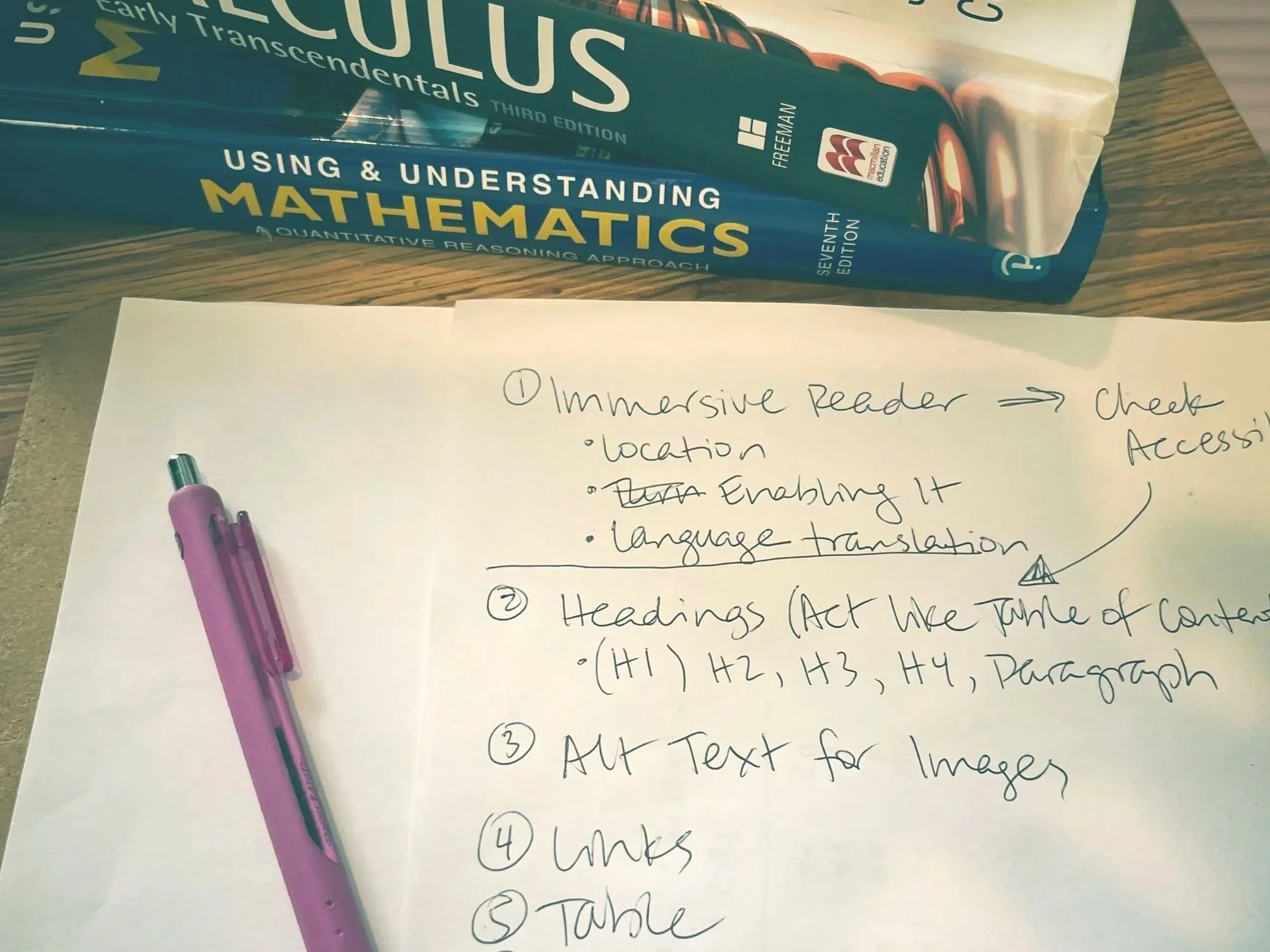Handwritten notes with a pen and two math books