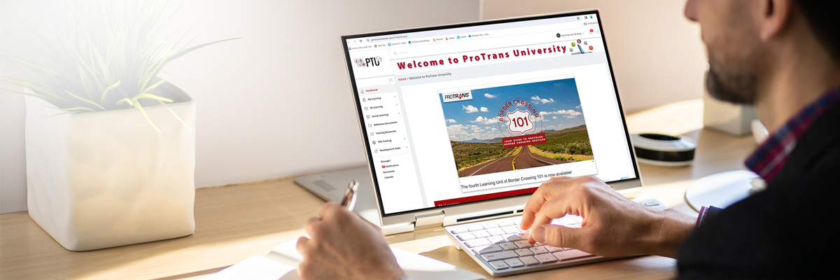 Person using a laptop on a desk, viewing the ProTrans University website about border crossing 101 with a potted plant nearby.
