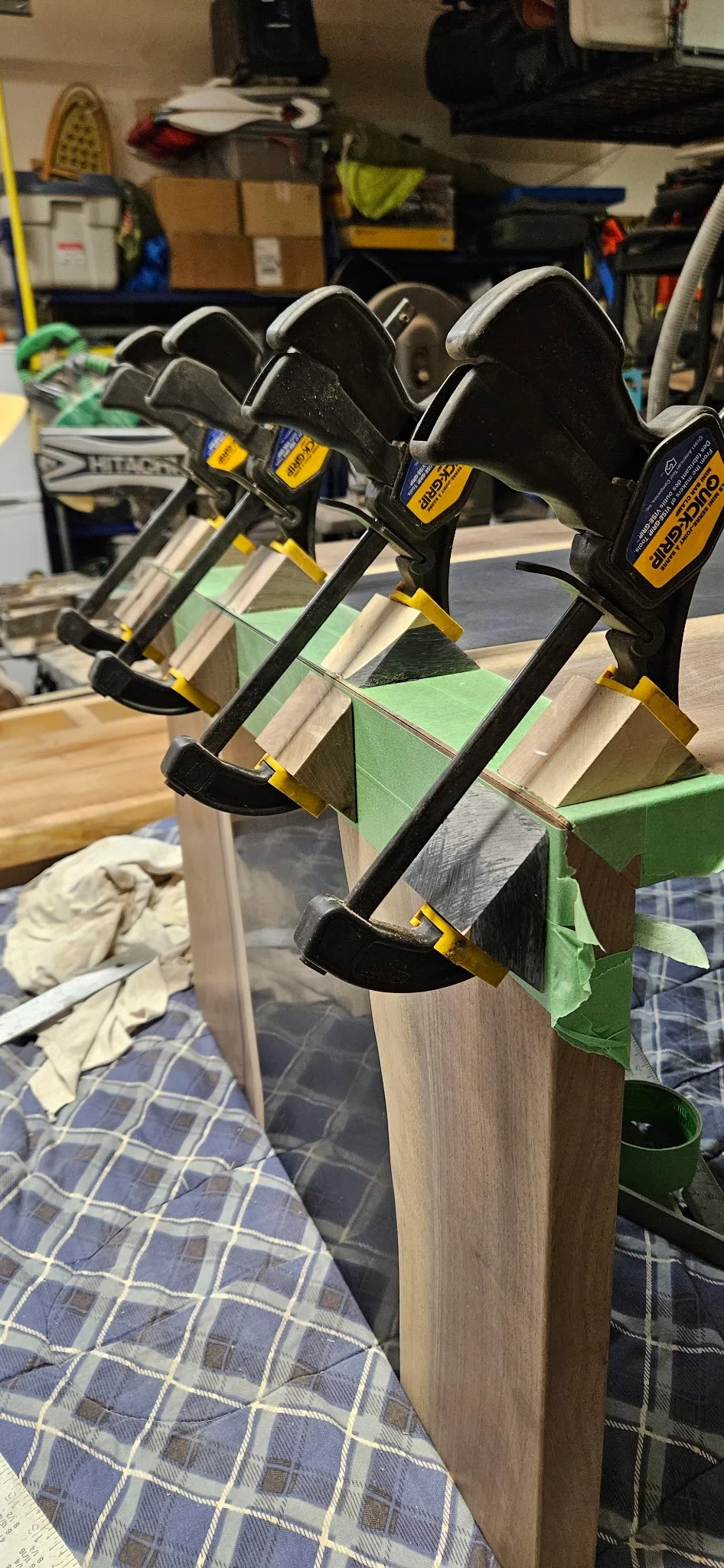 Set of woodworking clamps securing a piece of wood on a workbench in a garage or workshop.