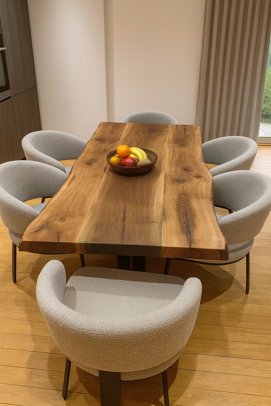 A wooden dining table with a bowl of fruit and six gray upholstered chairs in a modern dining room with wooden flooring and a sliding glass door.