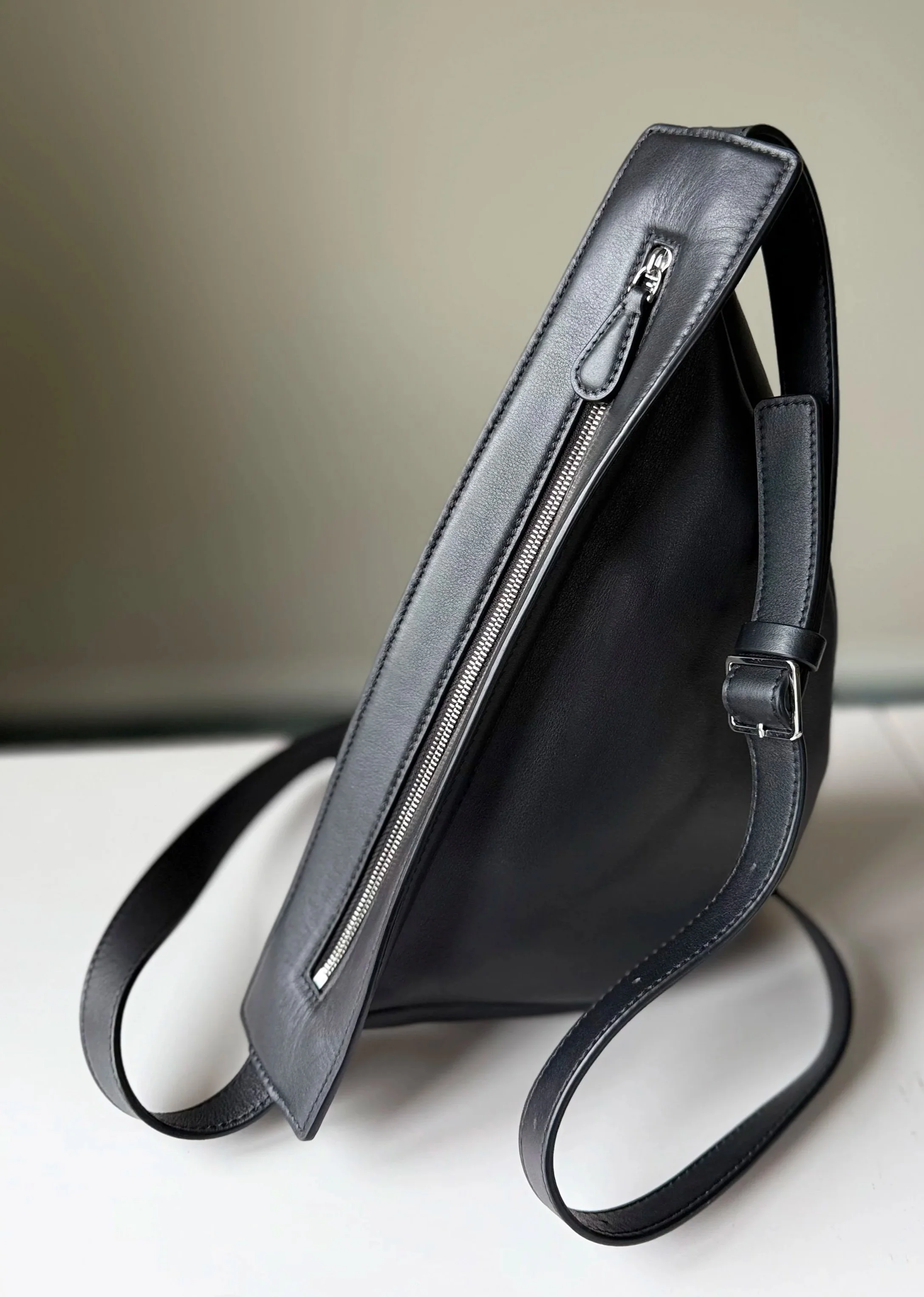 The Row Banana bag in black leather resting on a tabletop — showcased on Violetta’s Bags for its sculptural curve and understated elegance.