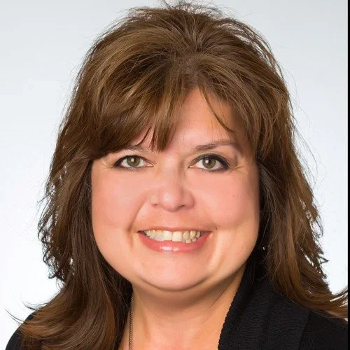 Headshot of a woman with shoulder-length brown hair, smiling, against a plain white background.