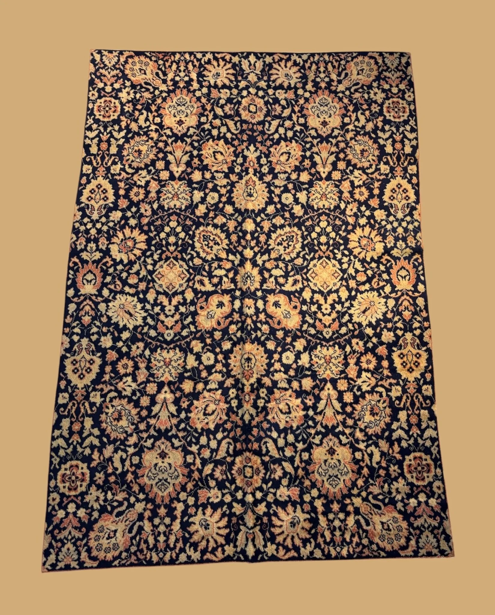 A detailed black Persian-style rug with floral and vine patterns in shades of beige, pink, and cream
