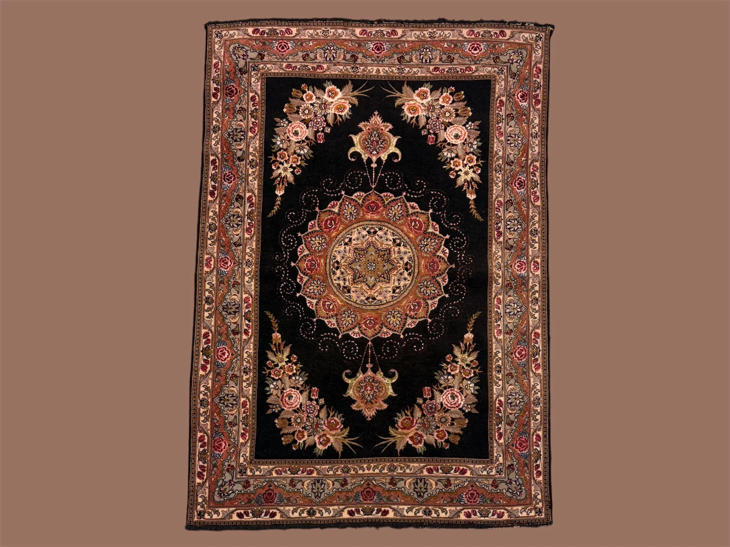 A traditional Persian-style rug with a central medallion and floral patterns in shades of beige, red, and gold on a black background, bordered by a floral design.
