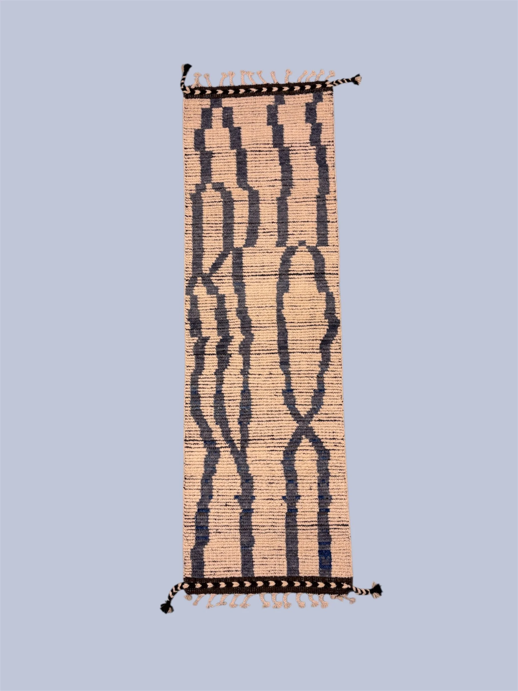 A woven textile or rug with a biblical scene of five figures, possibly shepherds or villagers, in black and beige colors.