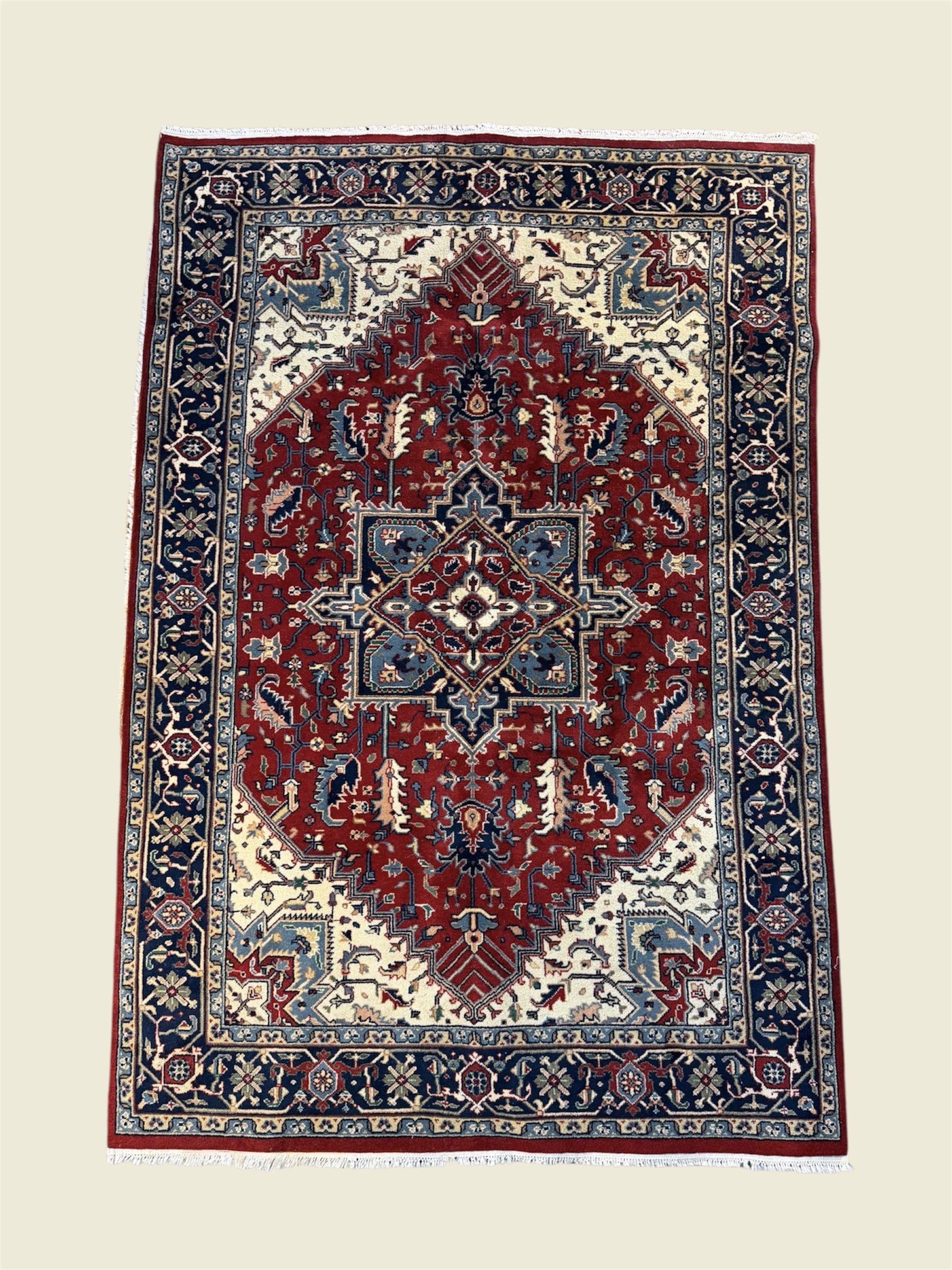 A traditional Persian-style area rug with intricate floral and geometric patterns in red, navy blue, cream, and light blue colors. The rug has a detailed border with floral motifs.