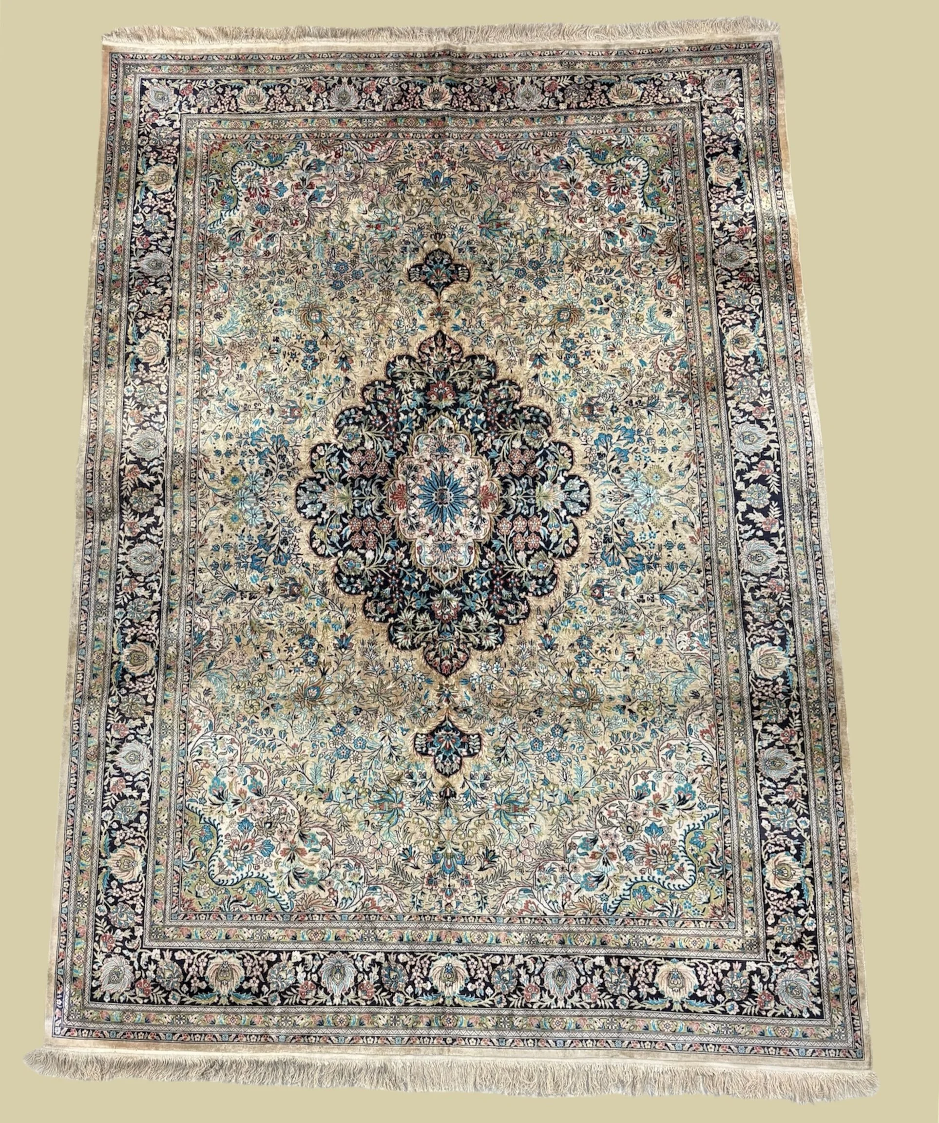 An ornate Persian-style rug with intricate floral and geometric patterns in black, beige, blue, red, and green, with fringes at the top and bottom.