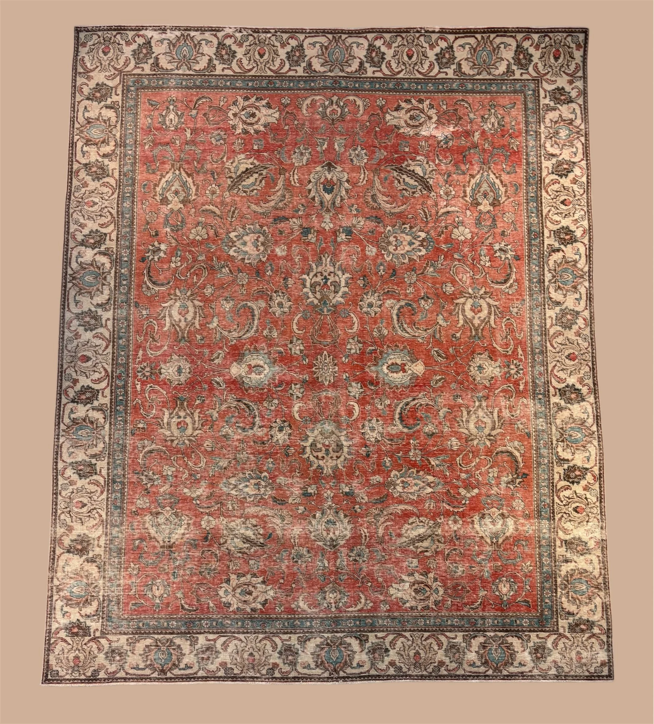 Close-up of a traditional floral patterned rug with a central red area surrounded by a beige border with floral motifs.