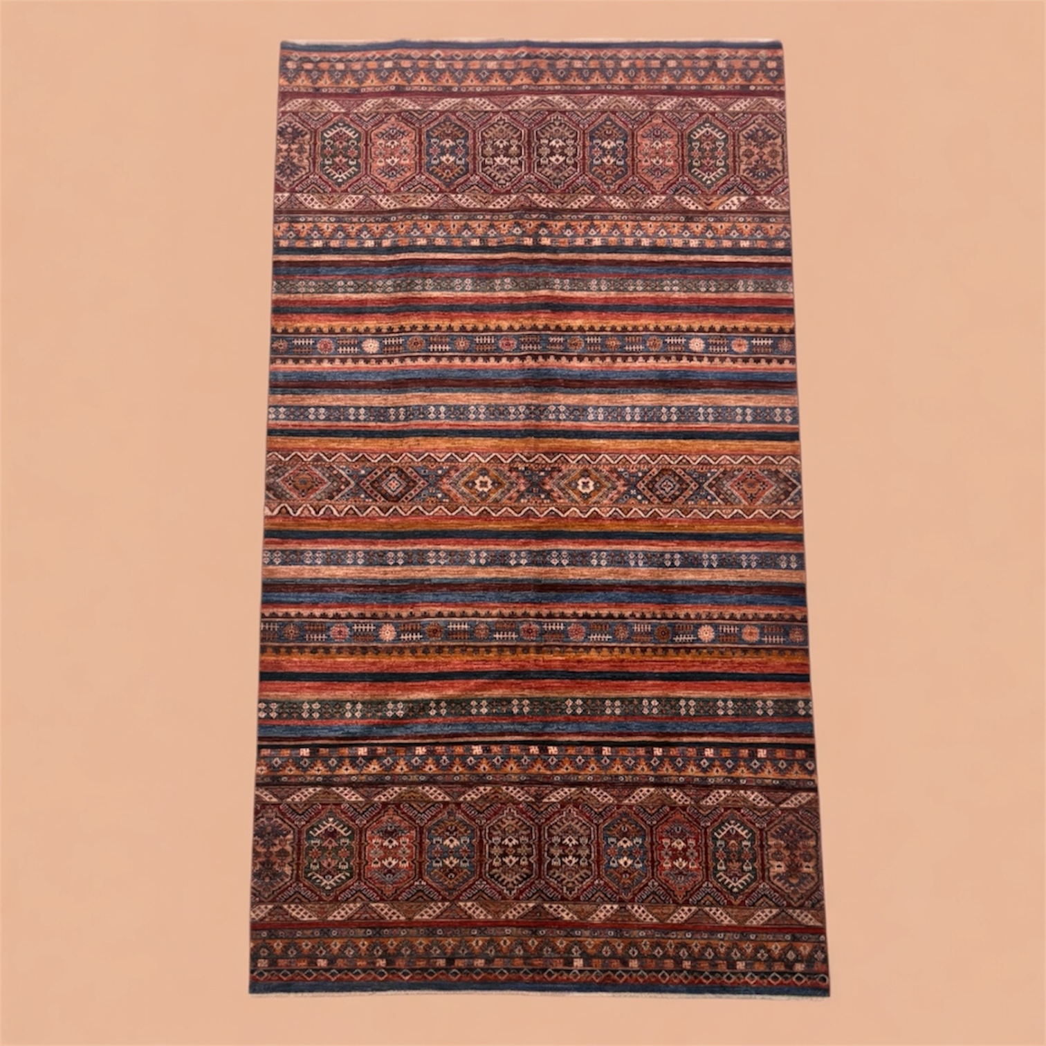 A detailed, colorful woven rug with geometric and floral patterns in shades of red, blue, orange, and beige, laid out flat against a plain background.