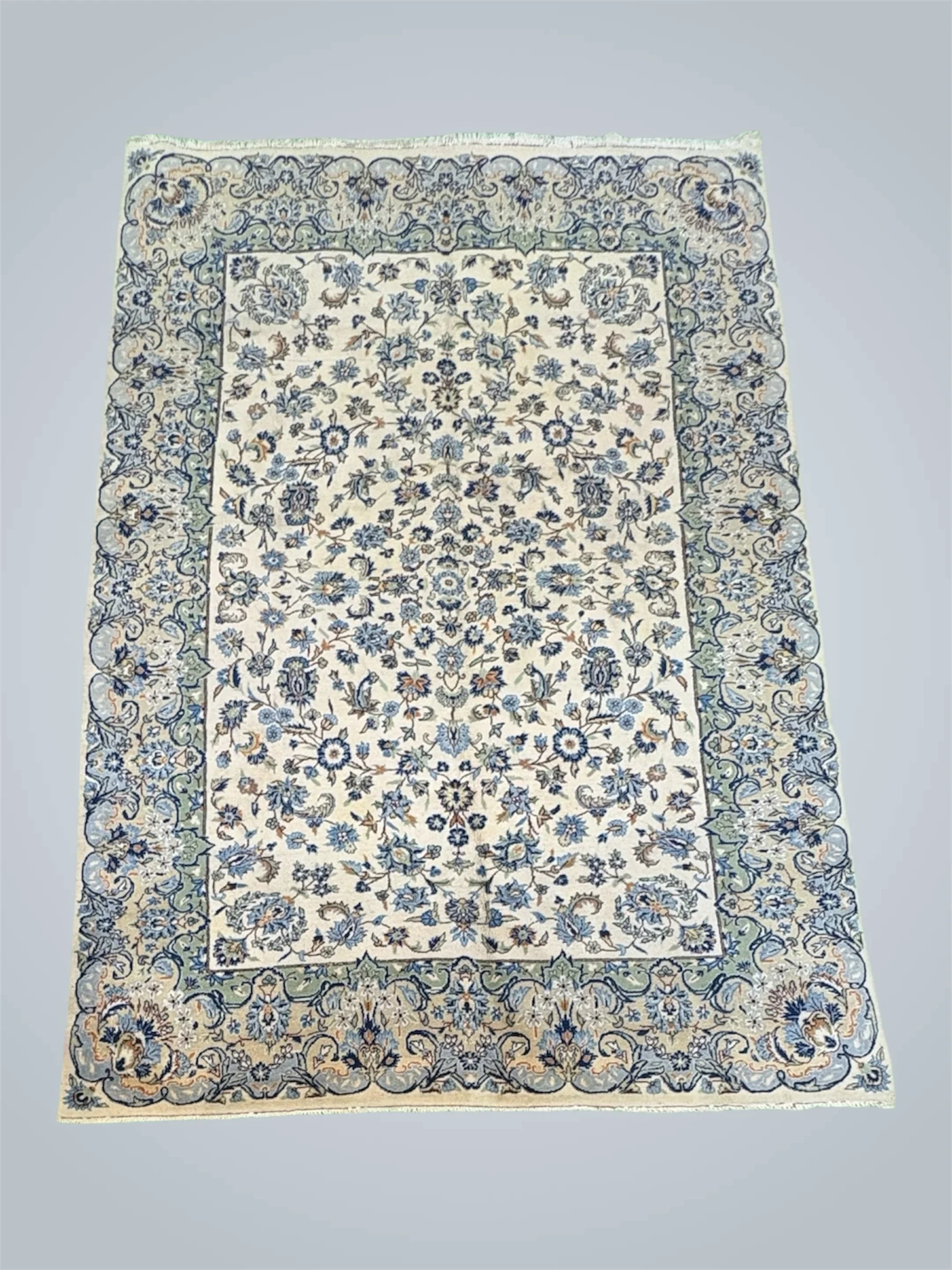 An ornate Persian-style area rug with intricate floral patterns in blue and cream colors, bordered with a detailed floral design.