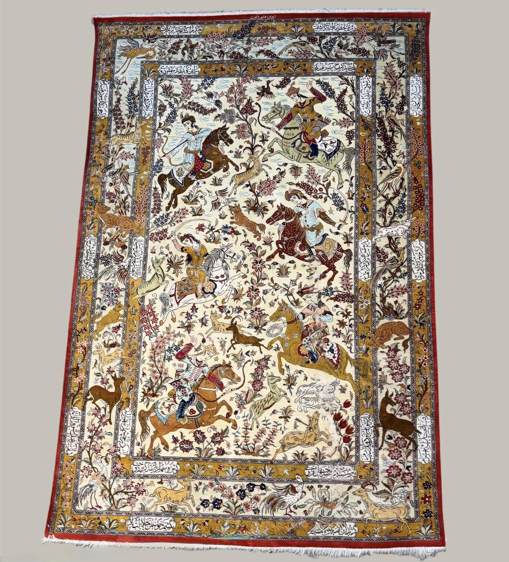 An intricate Persian-style rug with a central scene of two mounted warriors engaging in combat, surrounded by floral and animal motifs, and bordered with stylized Arabic script.