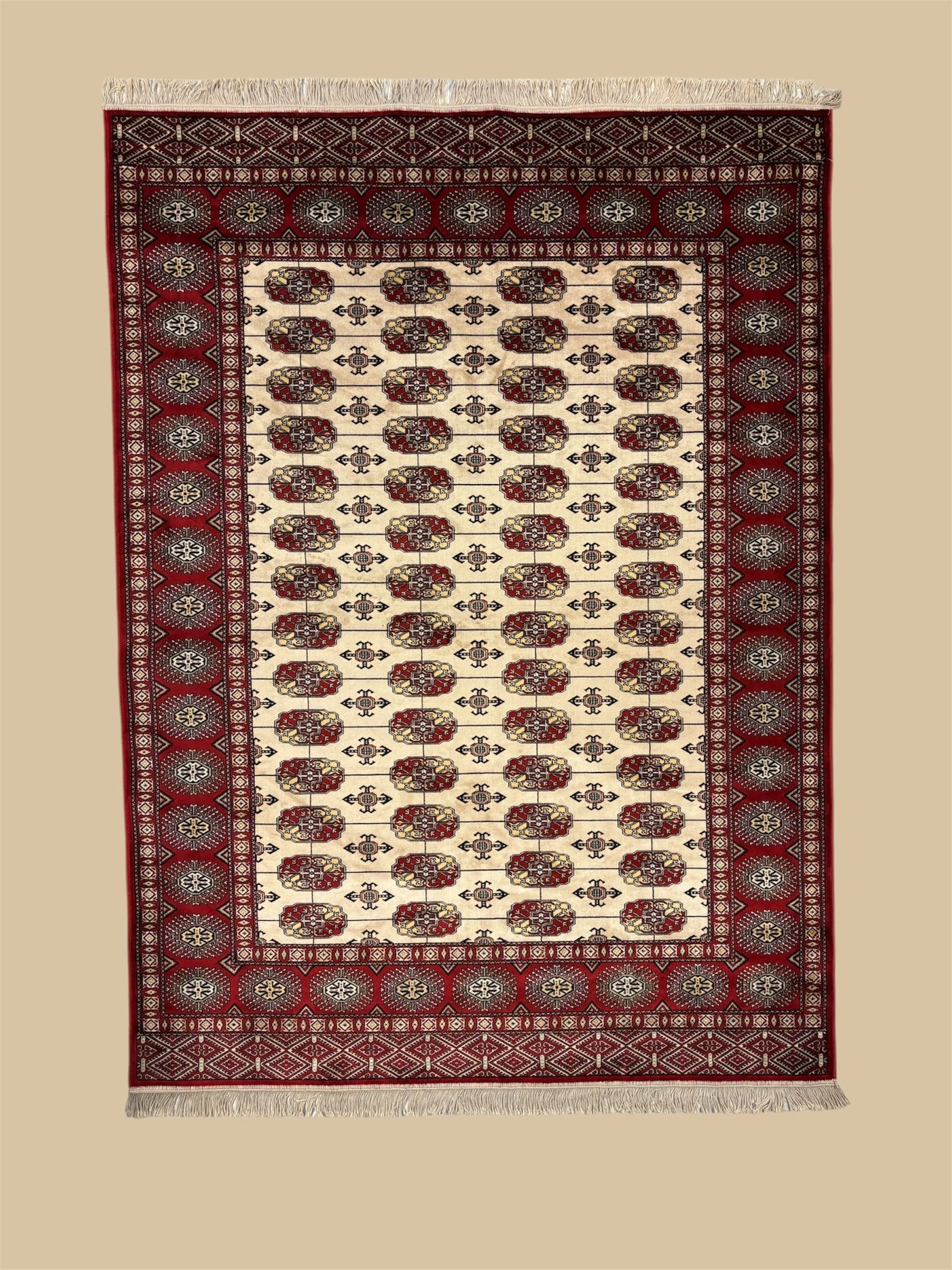 A traditional Persian-style rug with red, cream, black, and gold intricate geometric and floral patterns, bordered with a detailed design and fringes on both ends.