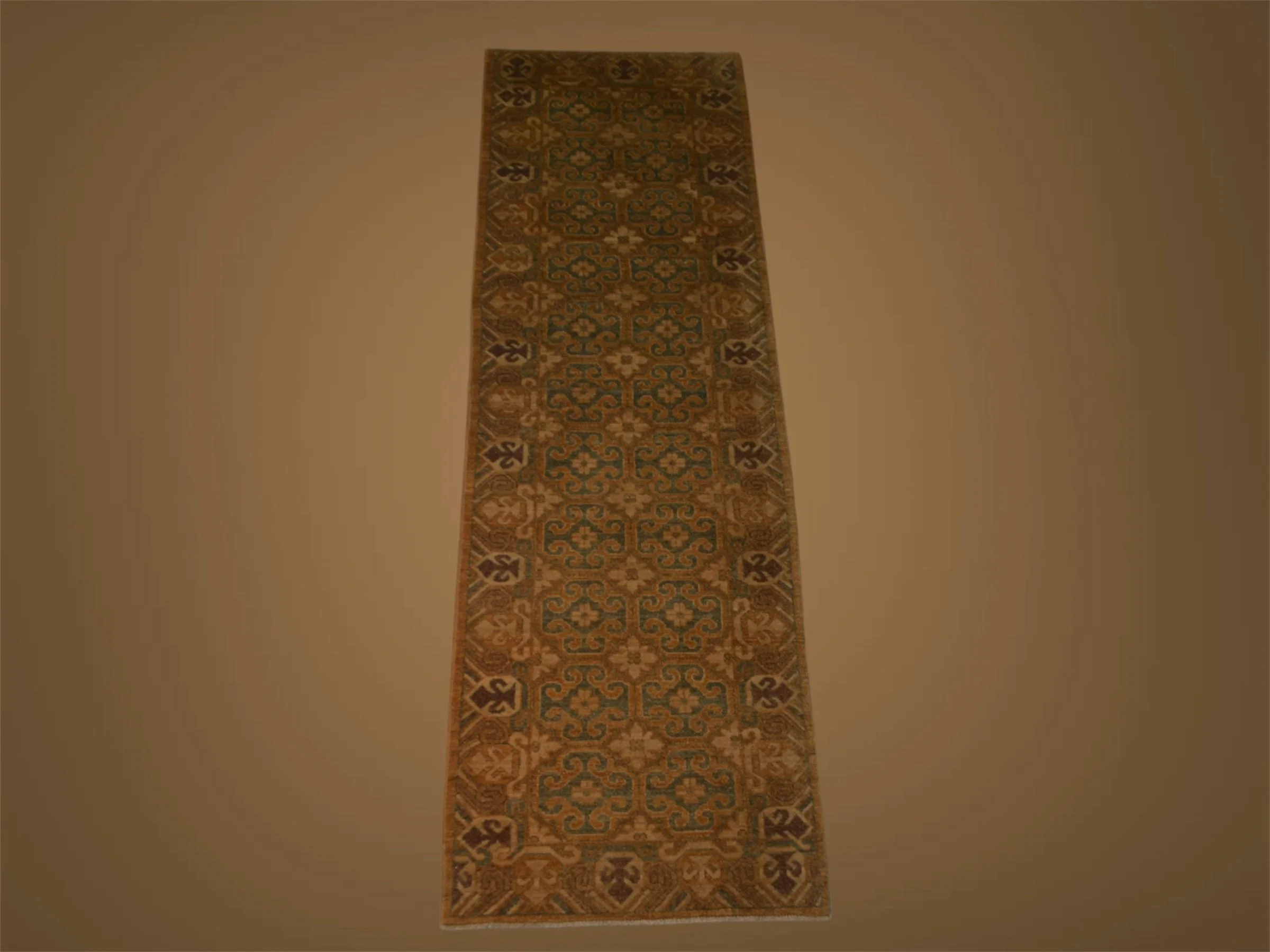 A long, ornate, patterned rug with geometric and floral designs in earthy tones, laid out on a plain beige floor.