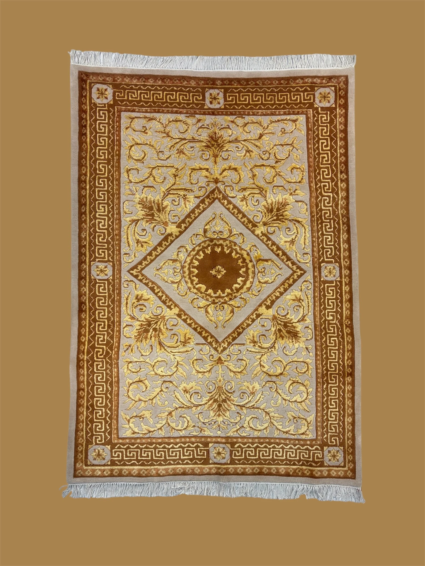 A traditional Persian-style rug with intricate gold, beige, and brown floral and geometric patterns, fringed edges, and a decorative border.
