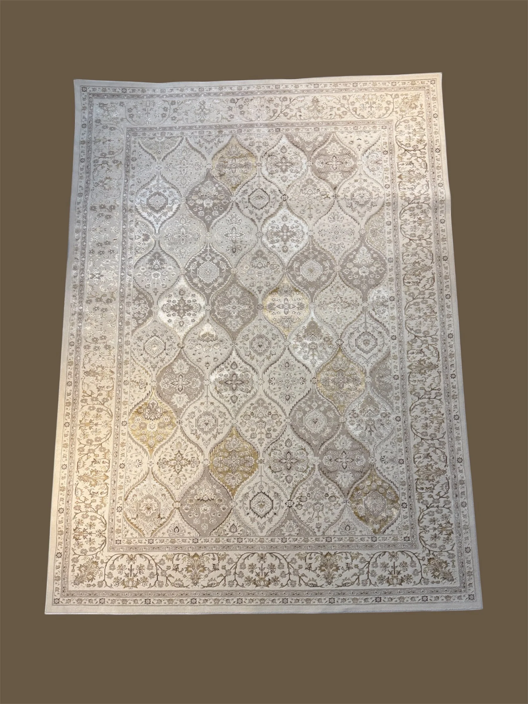 An ornate, light-colored area rug with intricate floral and geometric patterns, bordered by multiple decorative bands.