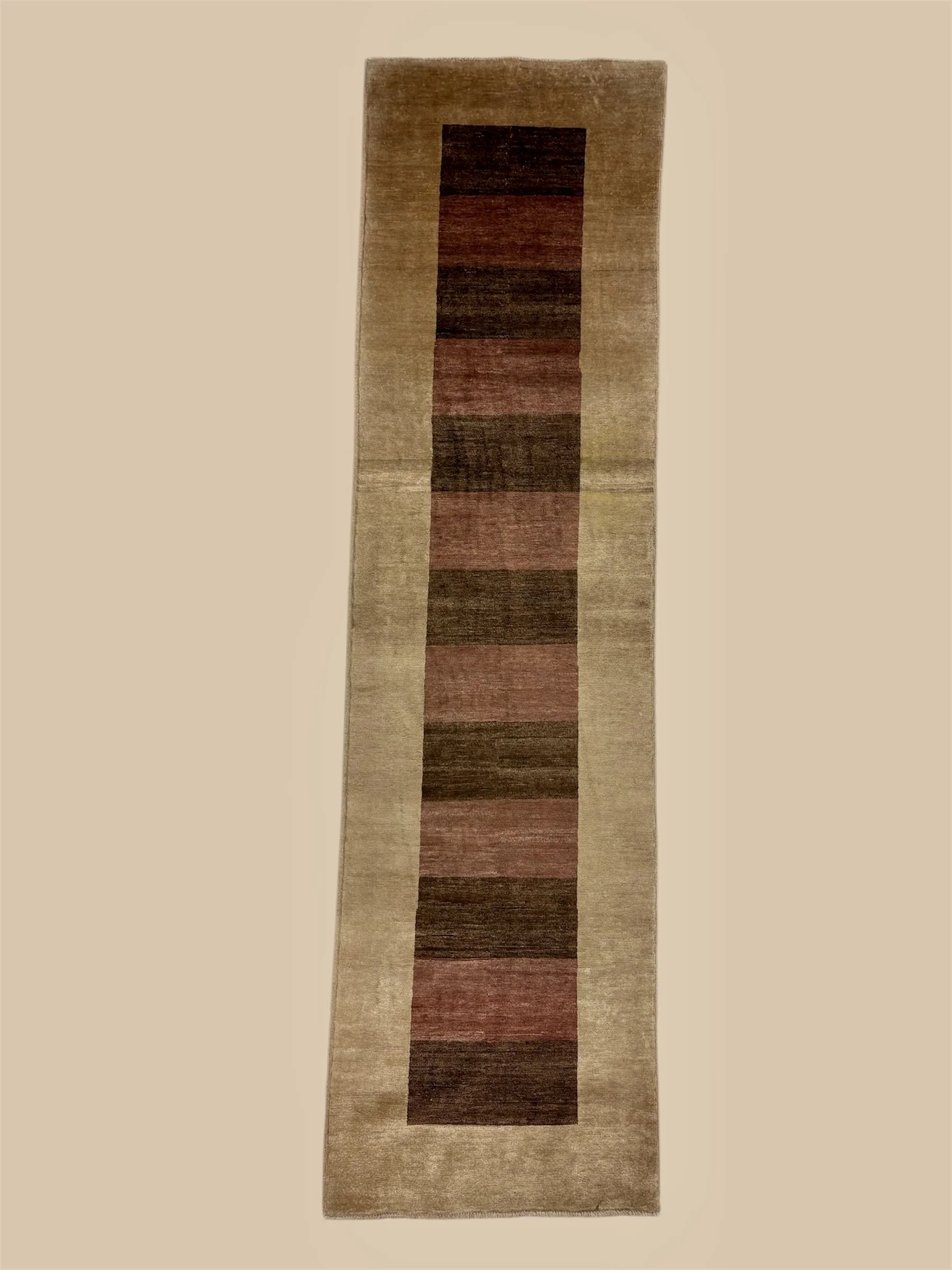 A rectangular area rug with a beige border and a central geometric pattern of horizontal stripes in various shades of brown, red, and black.