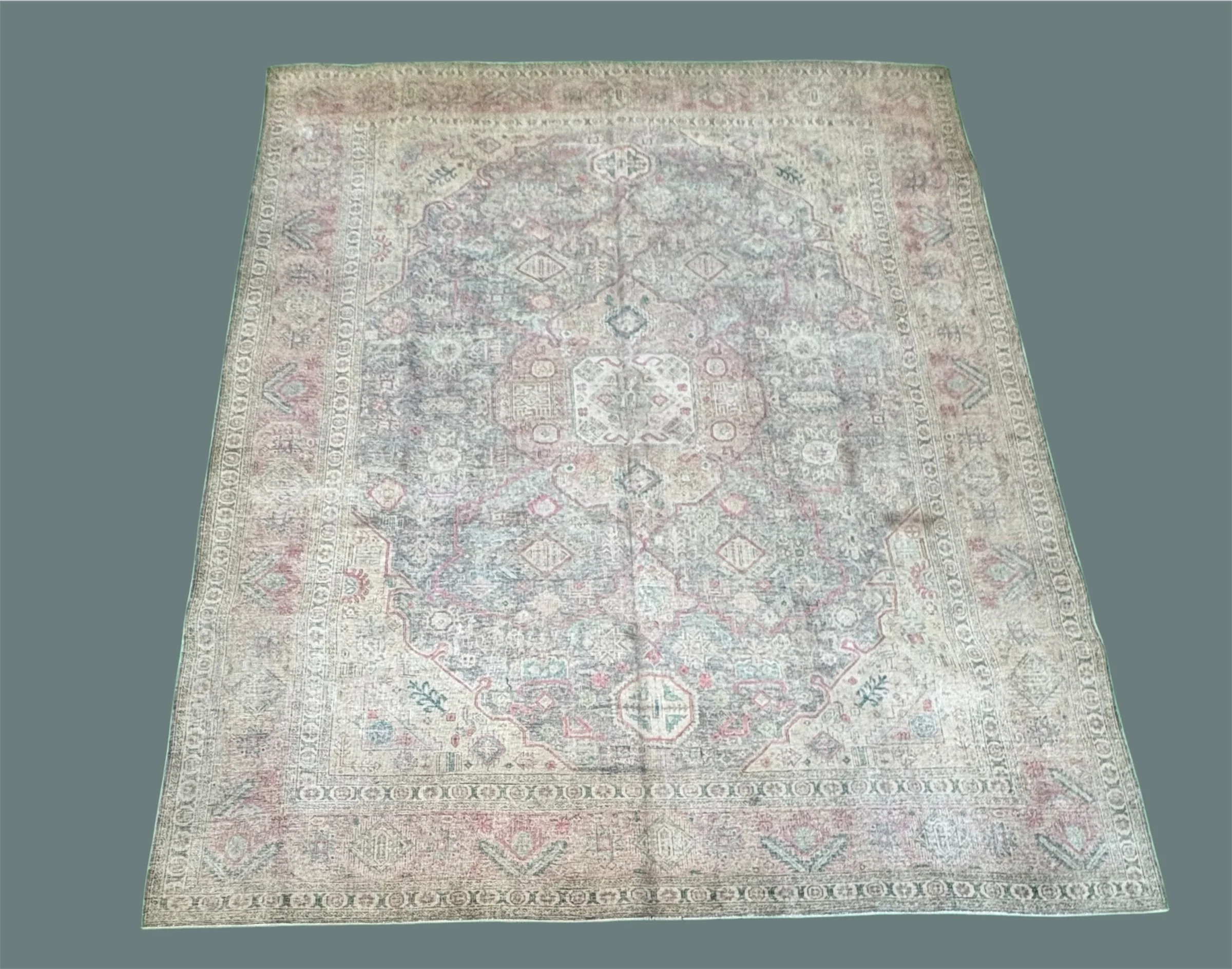 A vintage, intricately patterned area rug with faded pastel hues, featuring geometric and floral motifs in a traditional design.