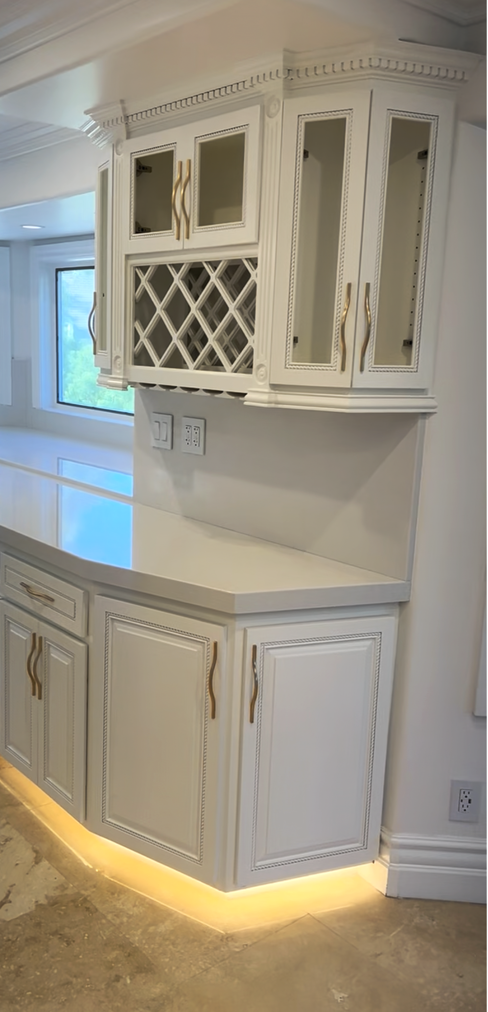 Kitchen cabinet with glass doors, wine rack, and under-cabinet lighting.