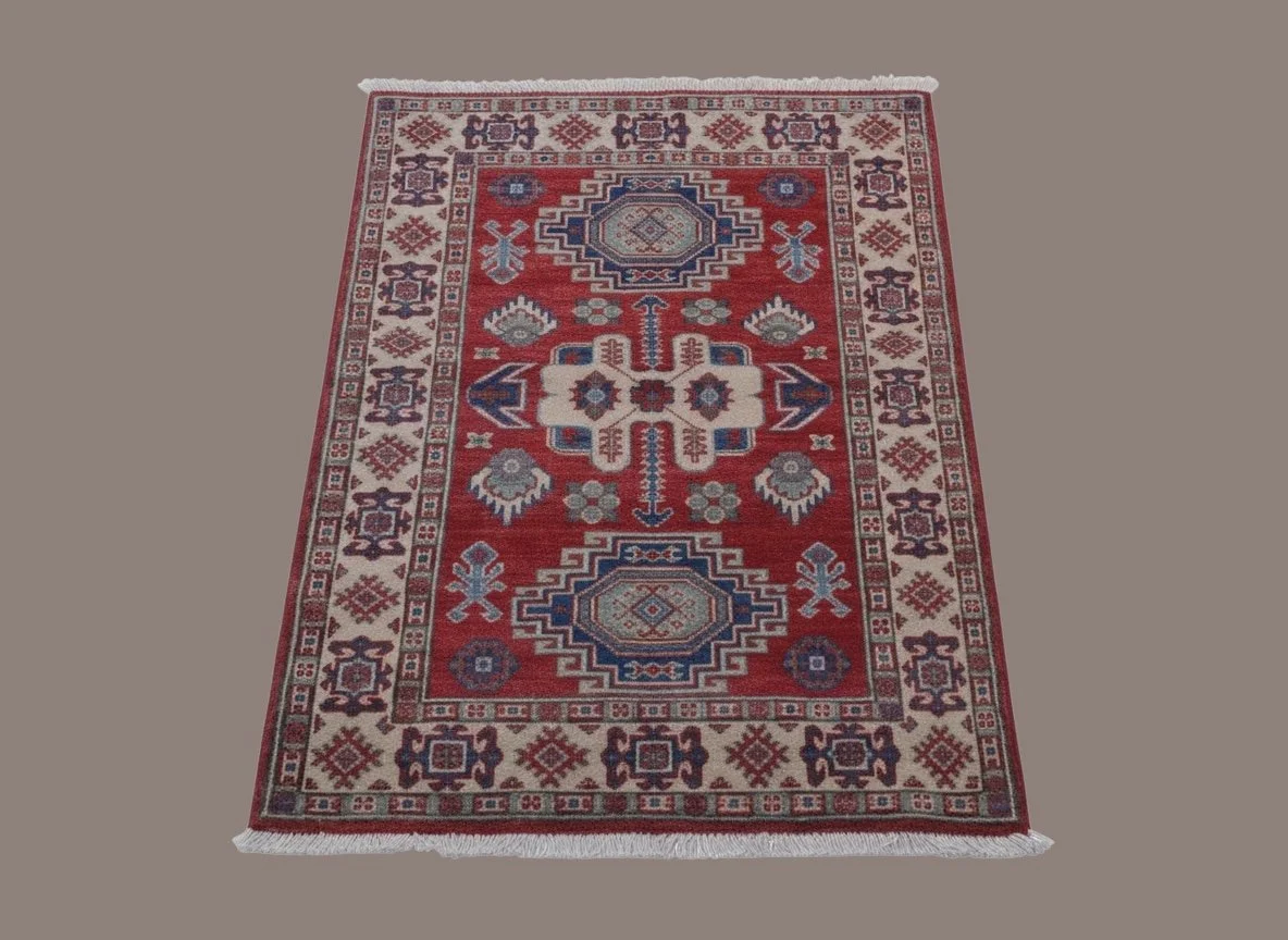 A colorful traditional patterned area rug with red, blue, cream, and purple colors on a plain beige background.