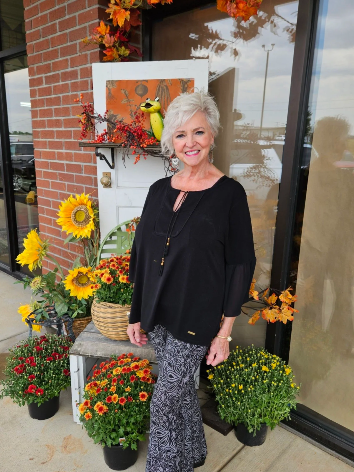 White haired woman in front of fall display, outside of home decor store