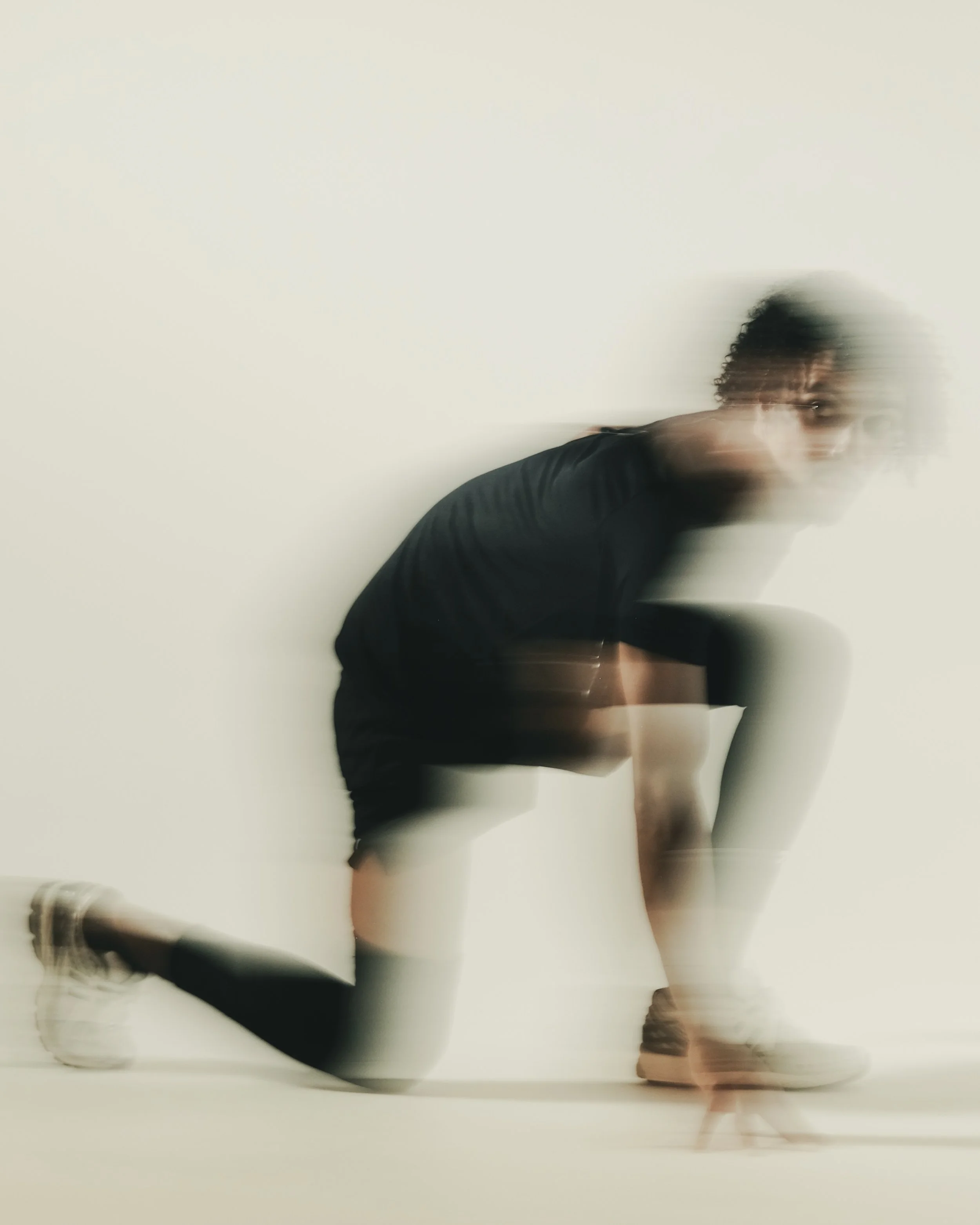 Person kneeling on the floor with a blurred motion effect against a plain white wall.