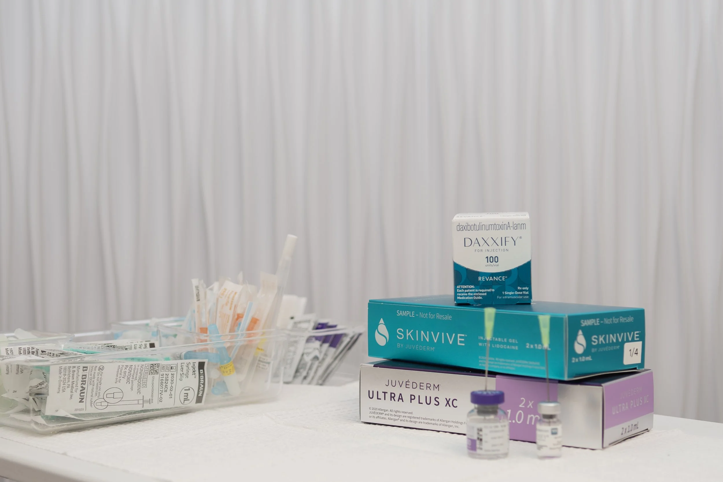 Woman receiving a cosmetic injection in her cheek, wearing a headband, with a healthcare professional holding the syringe.