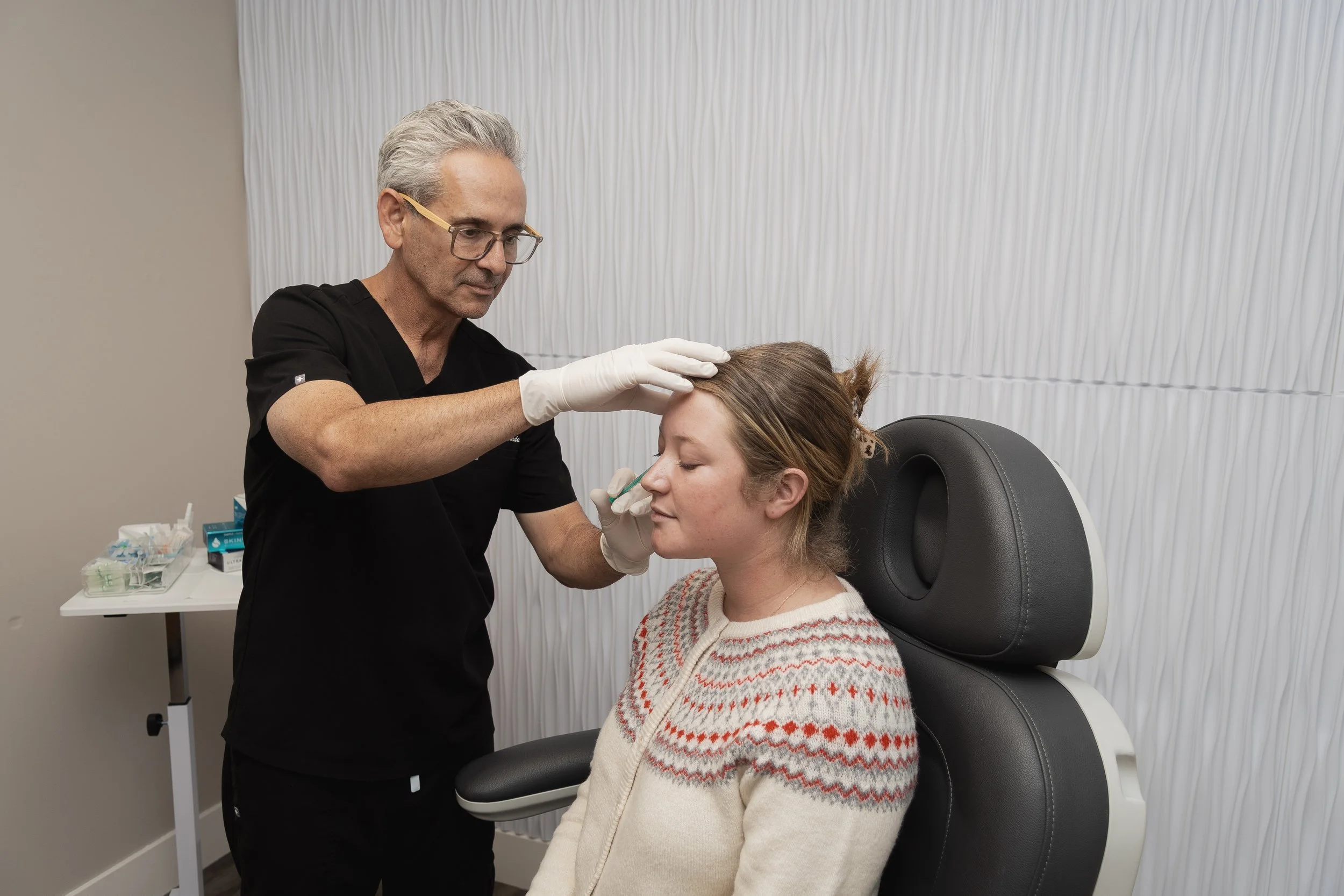 Doctor examining a woman's forehead in a medical office.