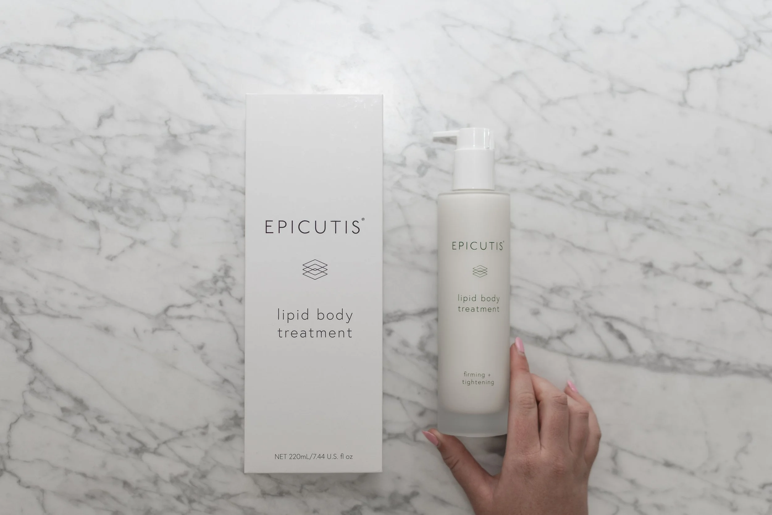 A white bottle of Epicuitis Lipid Body Treatment with a pump dispenser and a matching box, placed on a white marble surface.