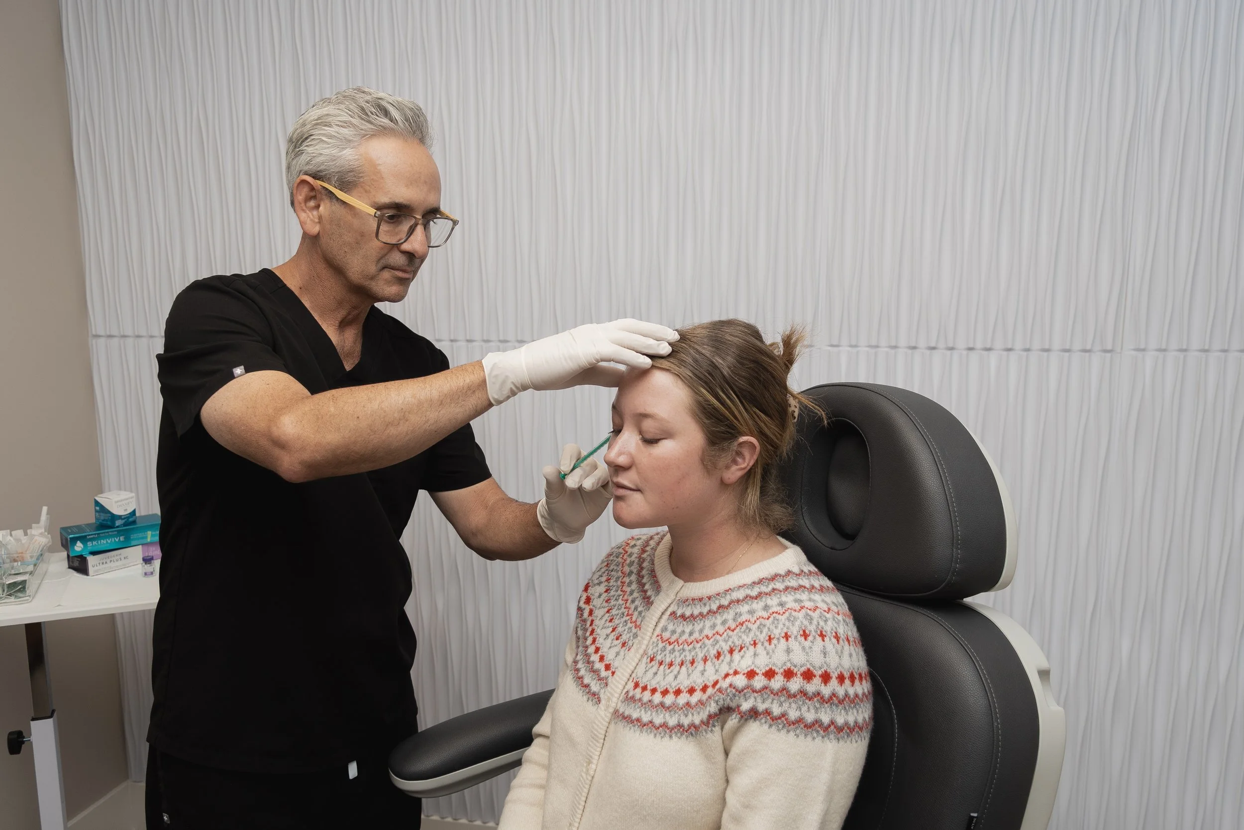 Medical professional administering a nasal spray to a woman in a clinical setting.
