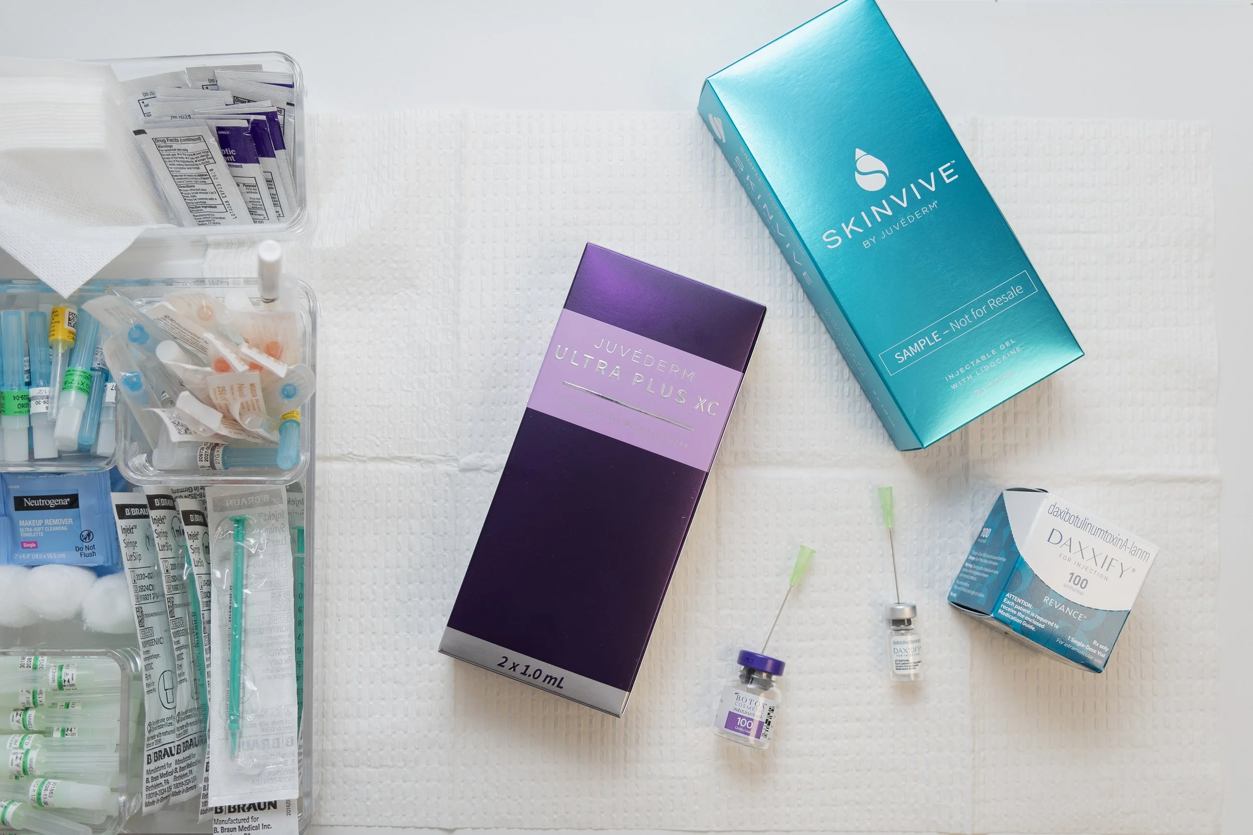 Medical supplies and injectables including syringes, vials, and boxes labeled Juvederm Ultra Plus XC, Skinvive, and Daxxify.