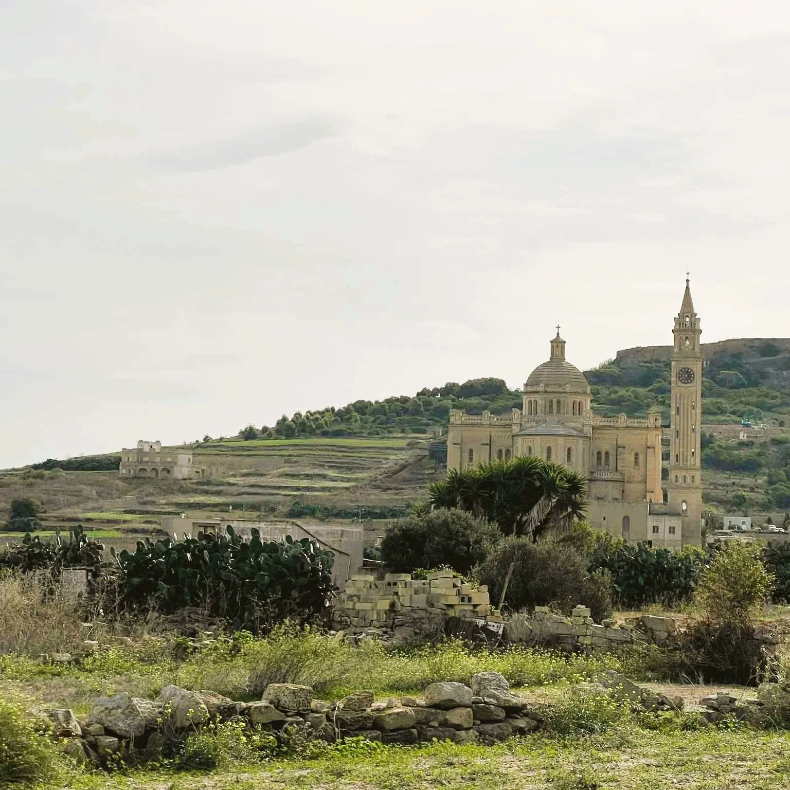Standing on a rock looking out over the sea and large rocks in the sea as the sun sets.